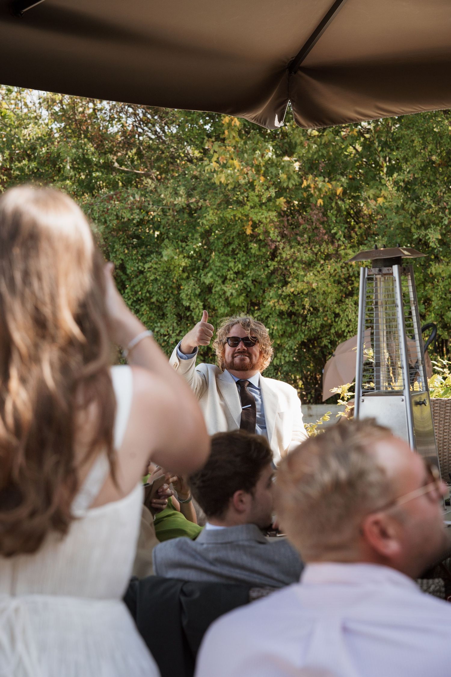 Wedding guests gather under canopy during outdoor reception celebration.