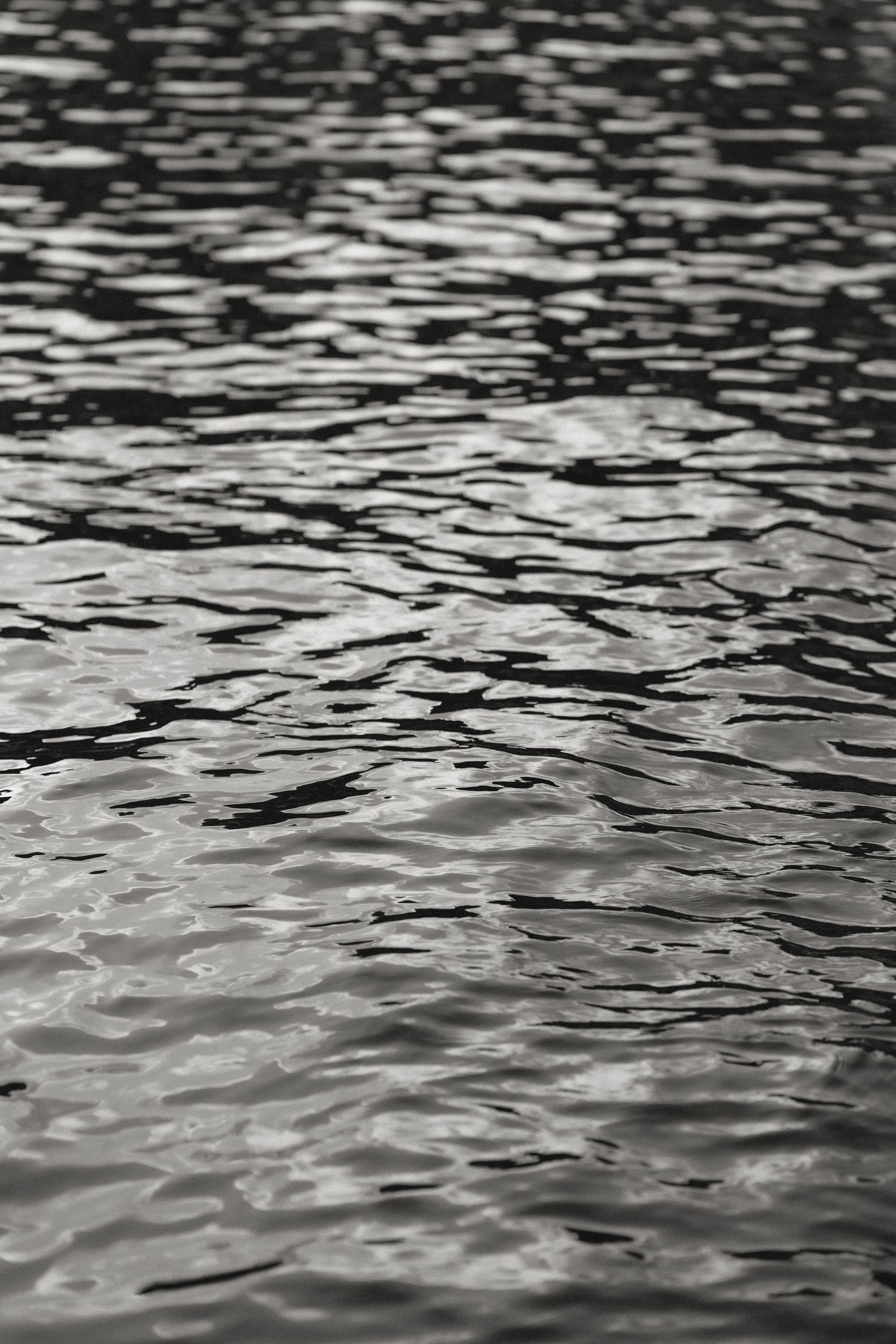 Abstract black and white pattern of sunlight reflecting on rippling water surface.