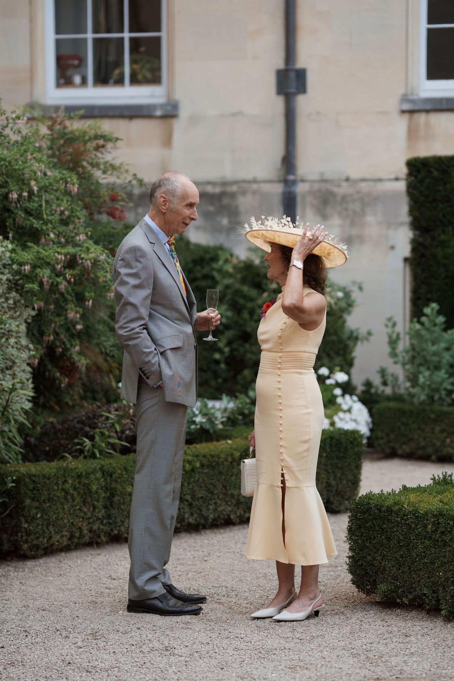 A playful moment in a garden setting with two people in formal attire.