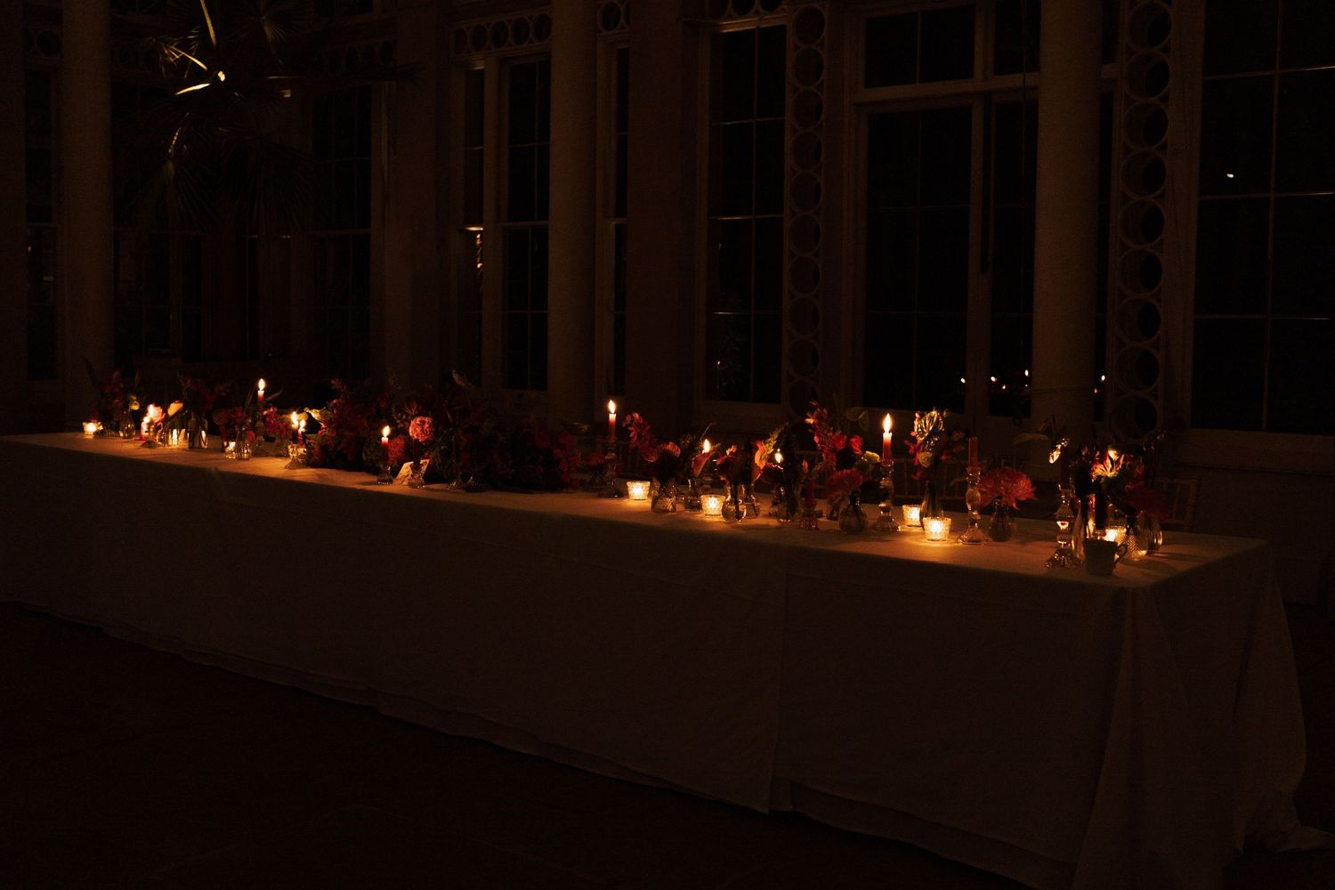 Row of glowing candles creating ambient lighting at an evening wedding reception.
