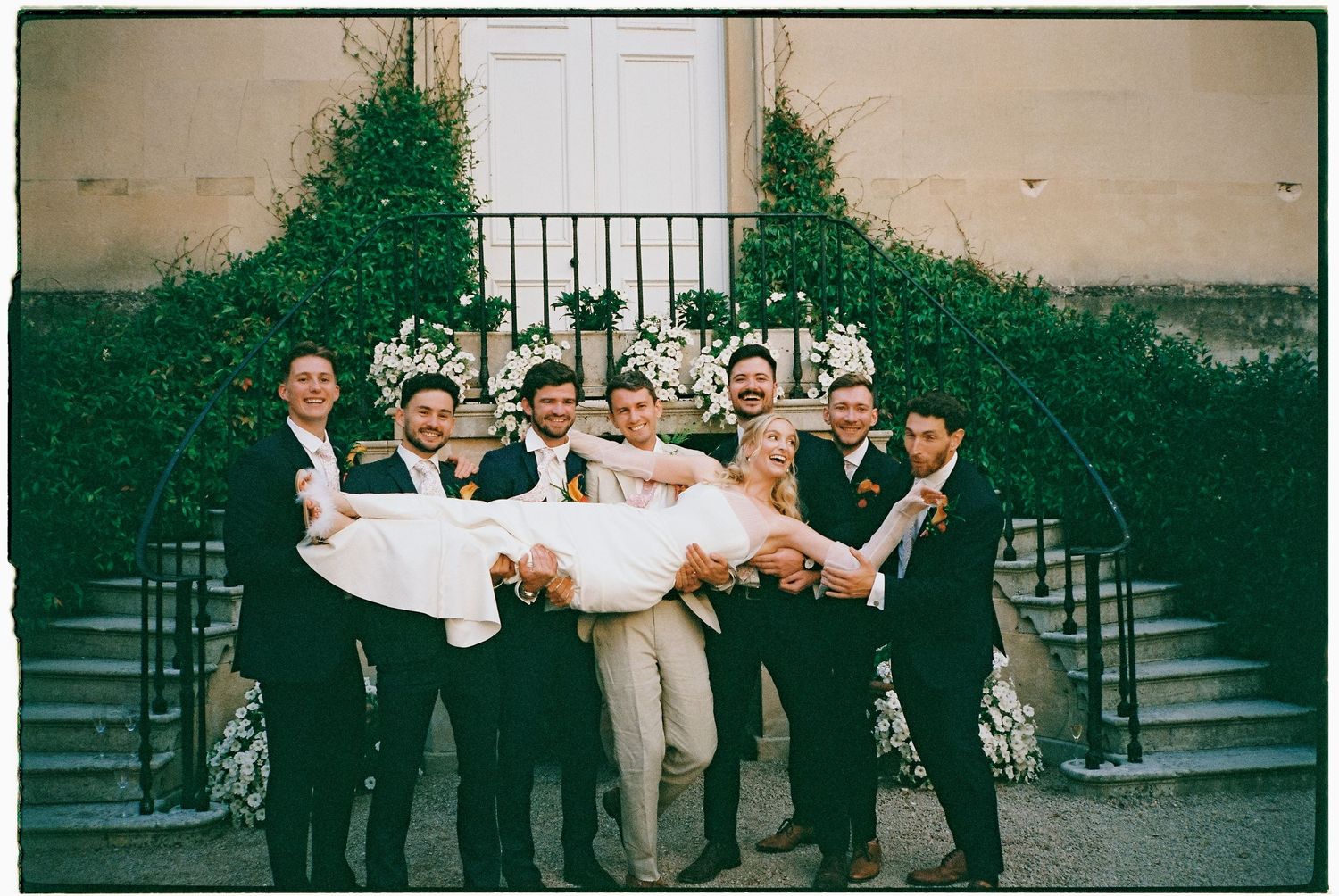 A group of formally dressed people celebrating outdoors in a joyful moment.