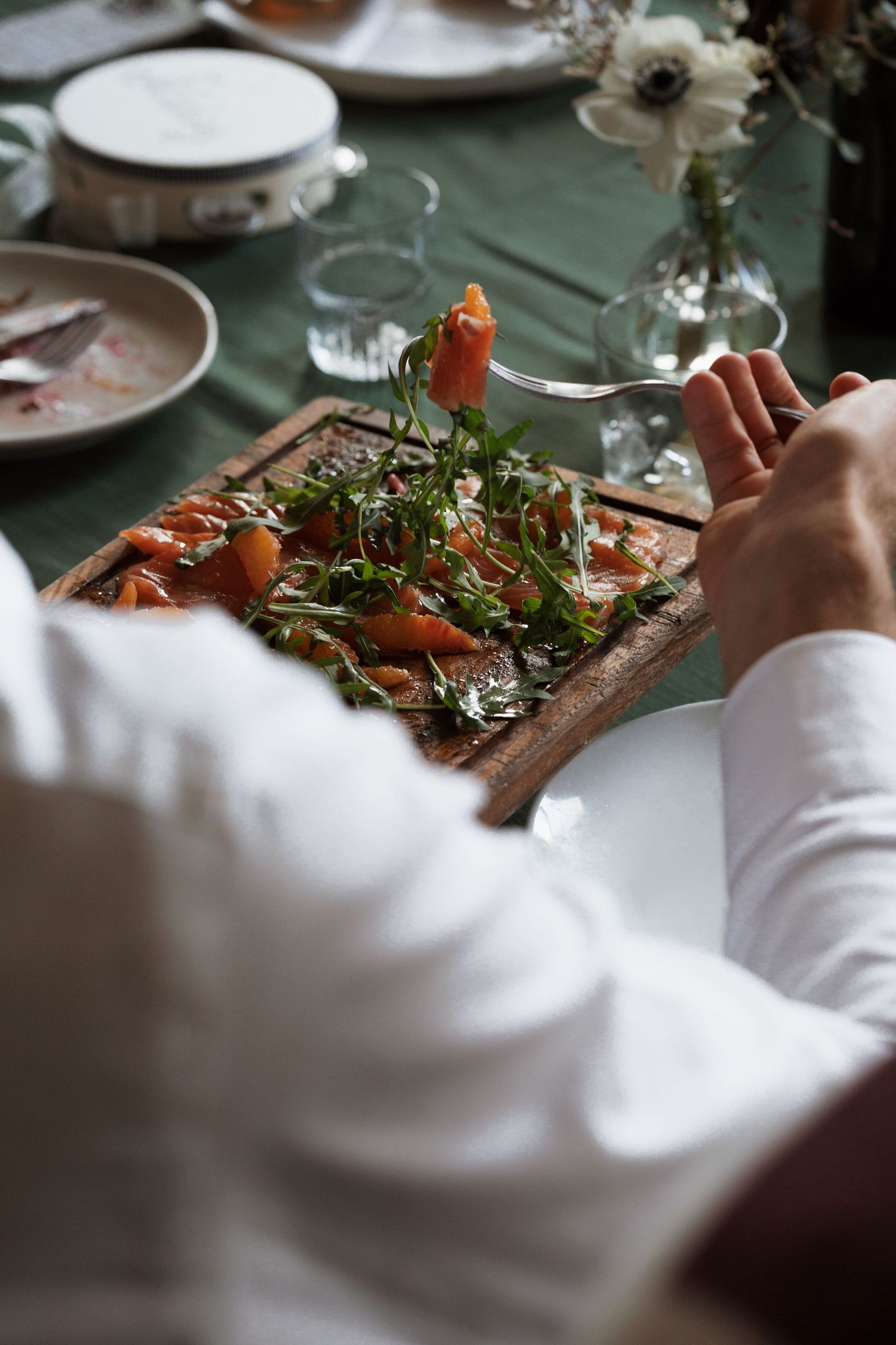 Fresh garnished dish being served on a rustic wooden board at an upscale dining event.