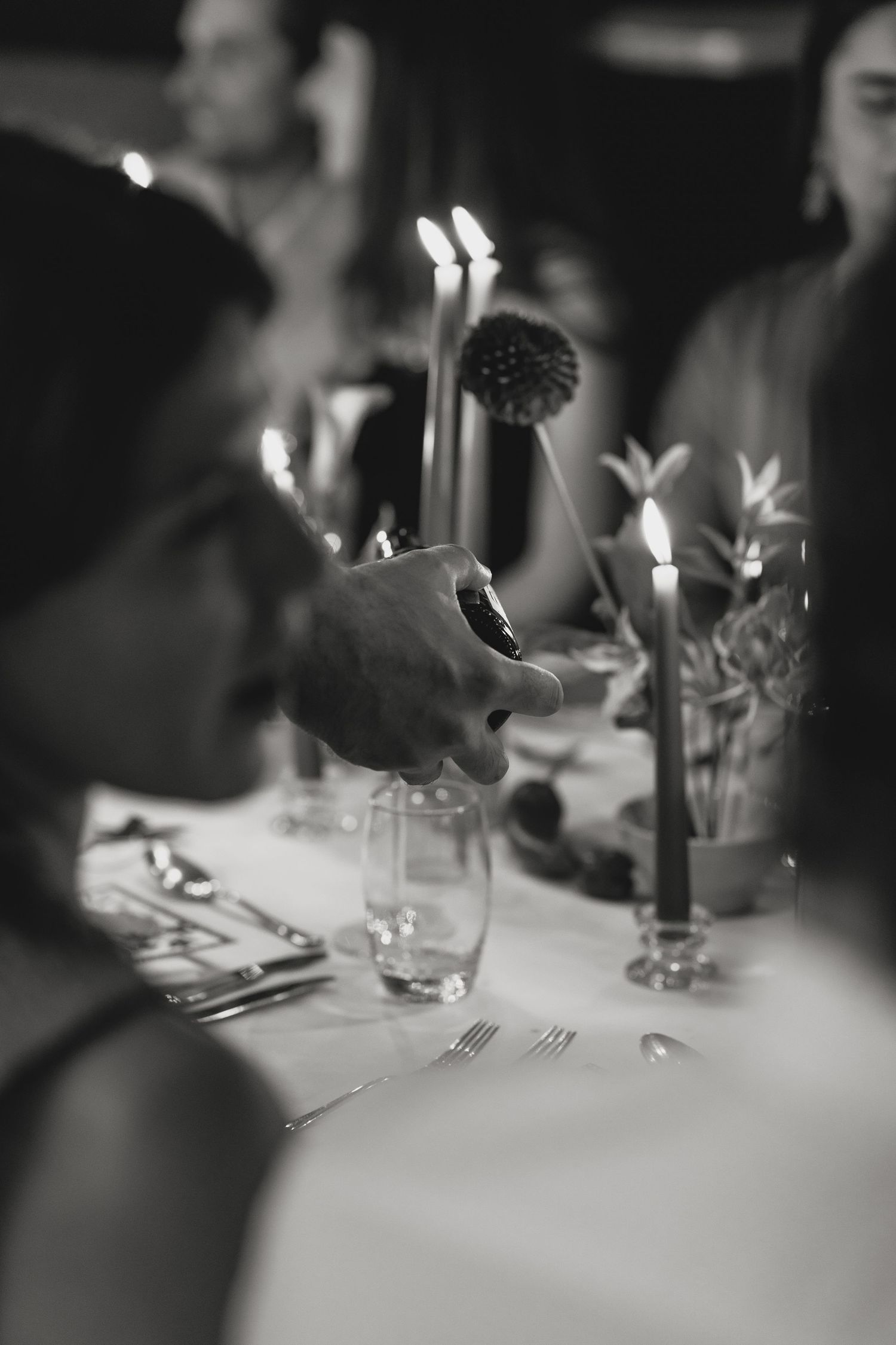 Artistic black and white shot of an elegant dinner table with candlelight and place settings.