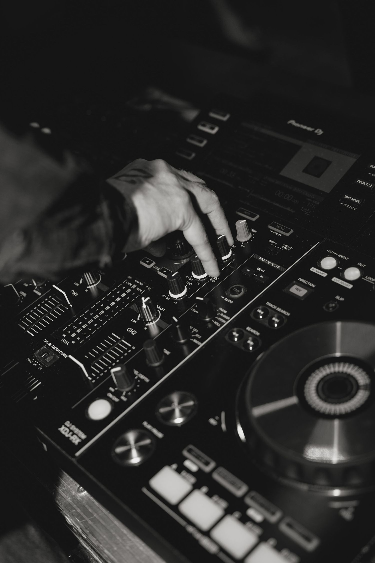 Close-up of DJ equipment and mixer controls in dark lighting.