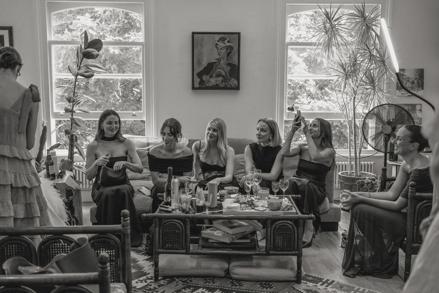 A casual gathering of friends in a sunlit living room with vintage decor and large windows.