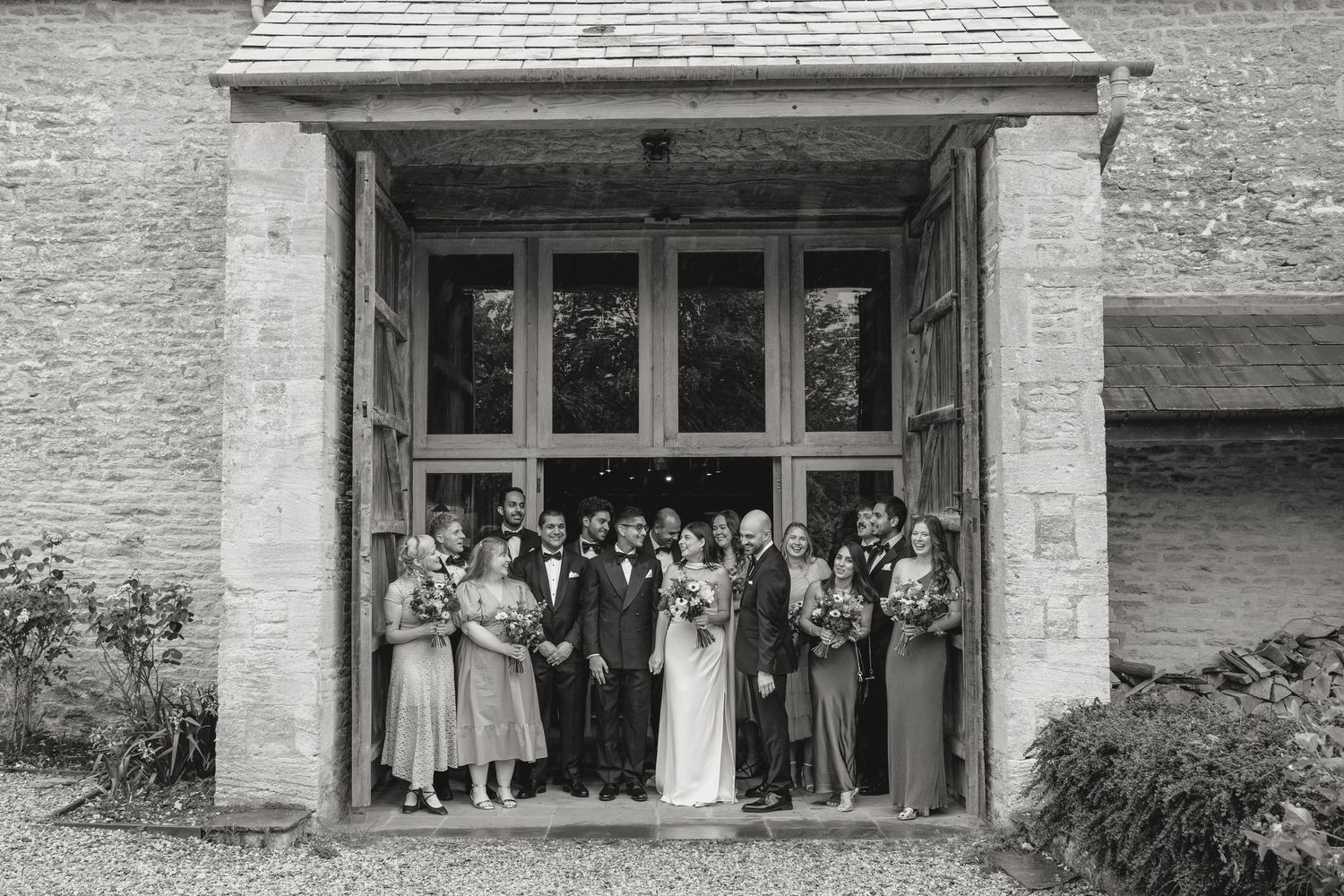 Stone building exterior with wedding guests gathered in the doorway for a group photo.