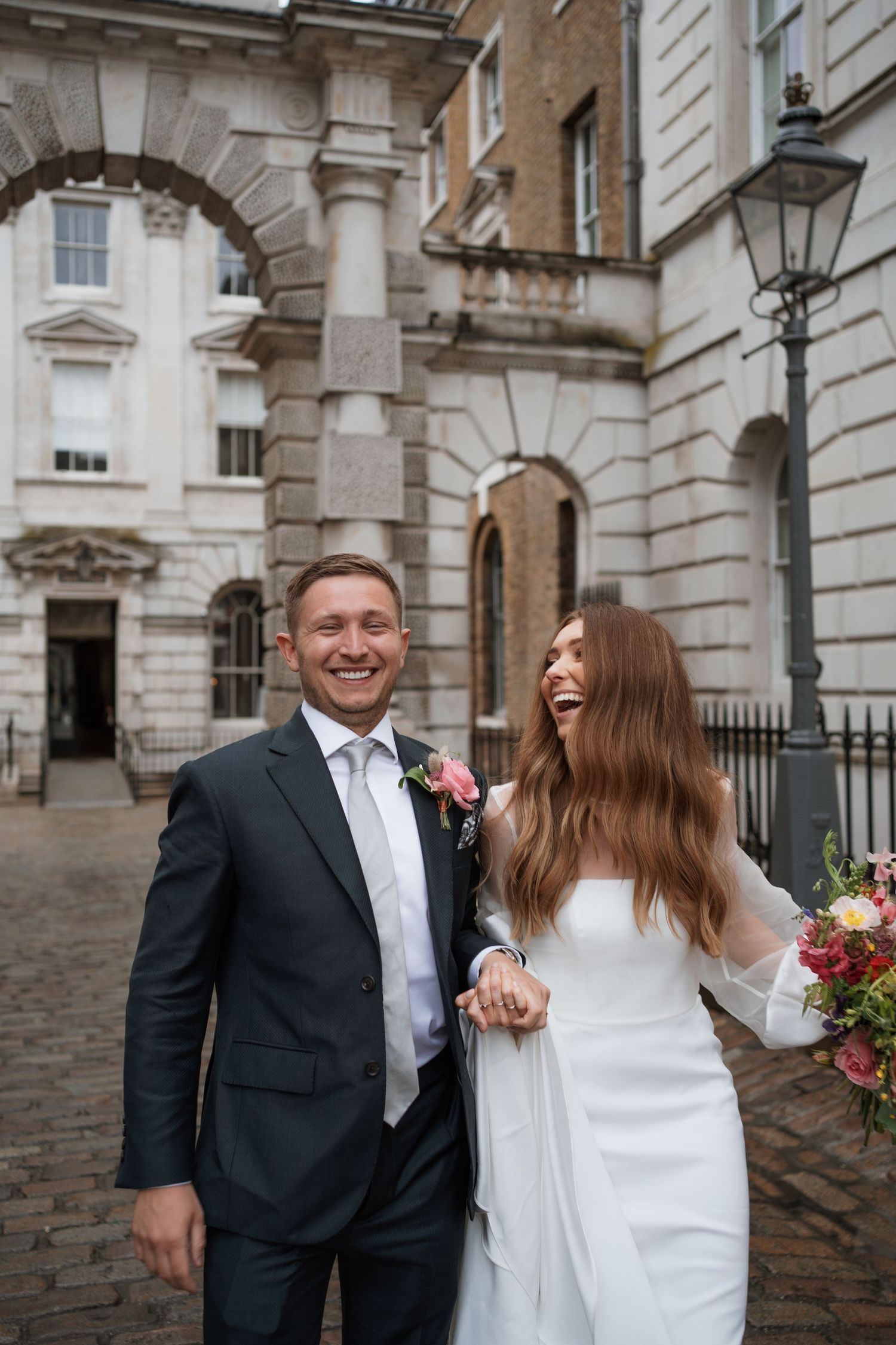 Couple sharing a joyful moment outside historic stone building.