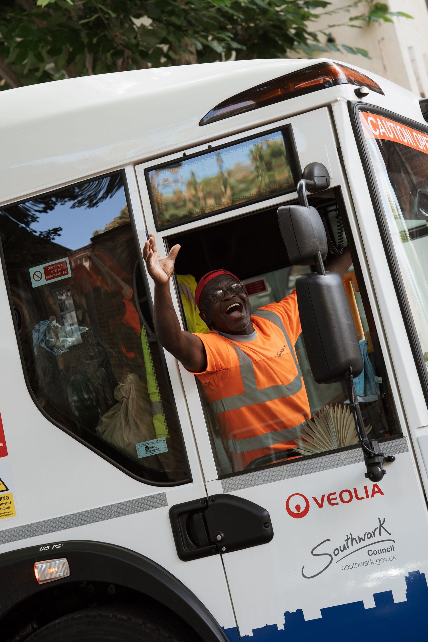 White Veolia service vehicles parked in a row with workers in high-visibility vests.