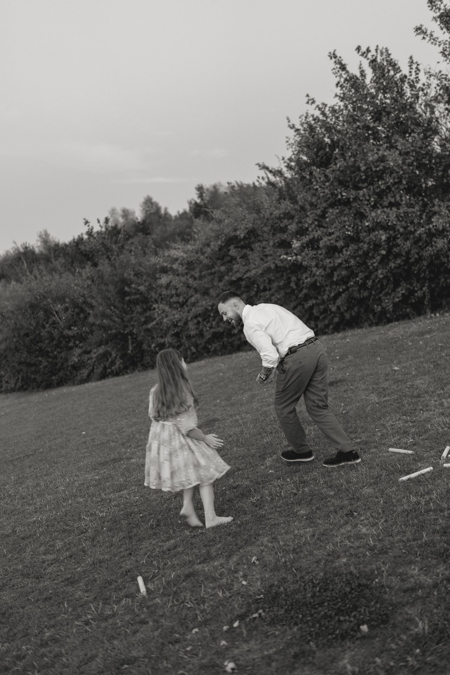 Black and white candid moment of playful interaction on grassy hillside.