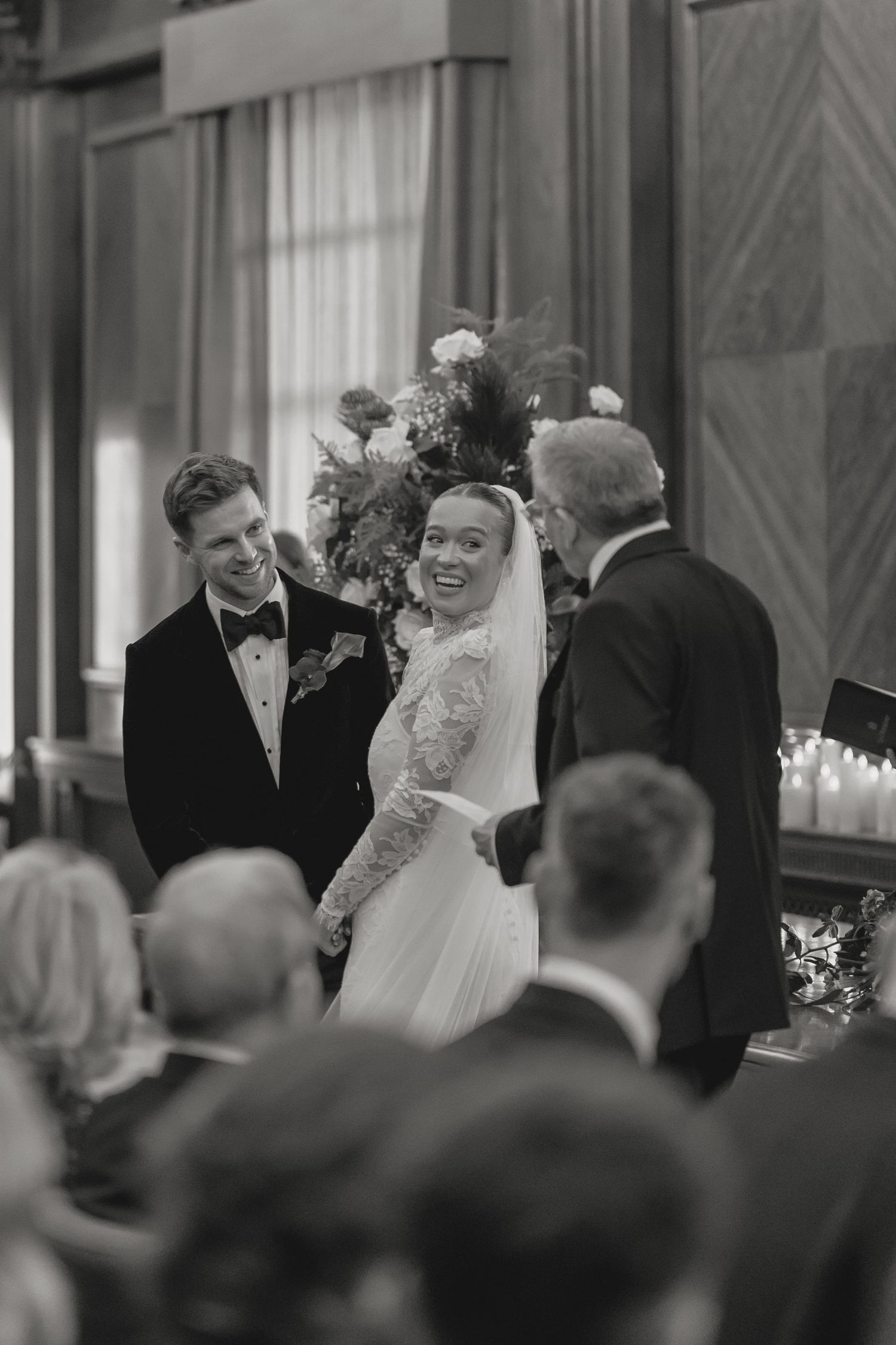 Wedding ceremony guests smile and celebrate during an emotional moment in an elegant venue.