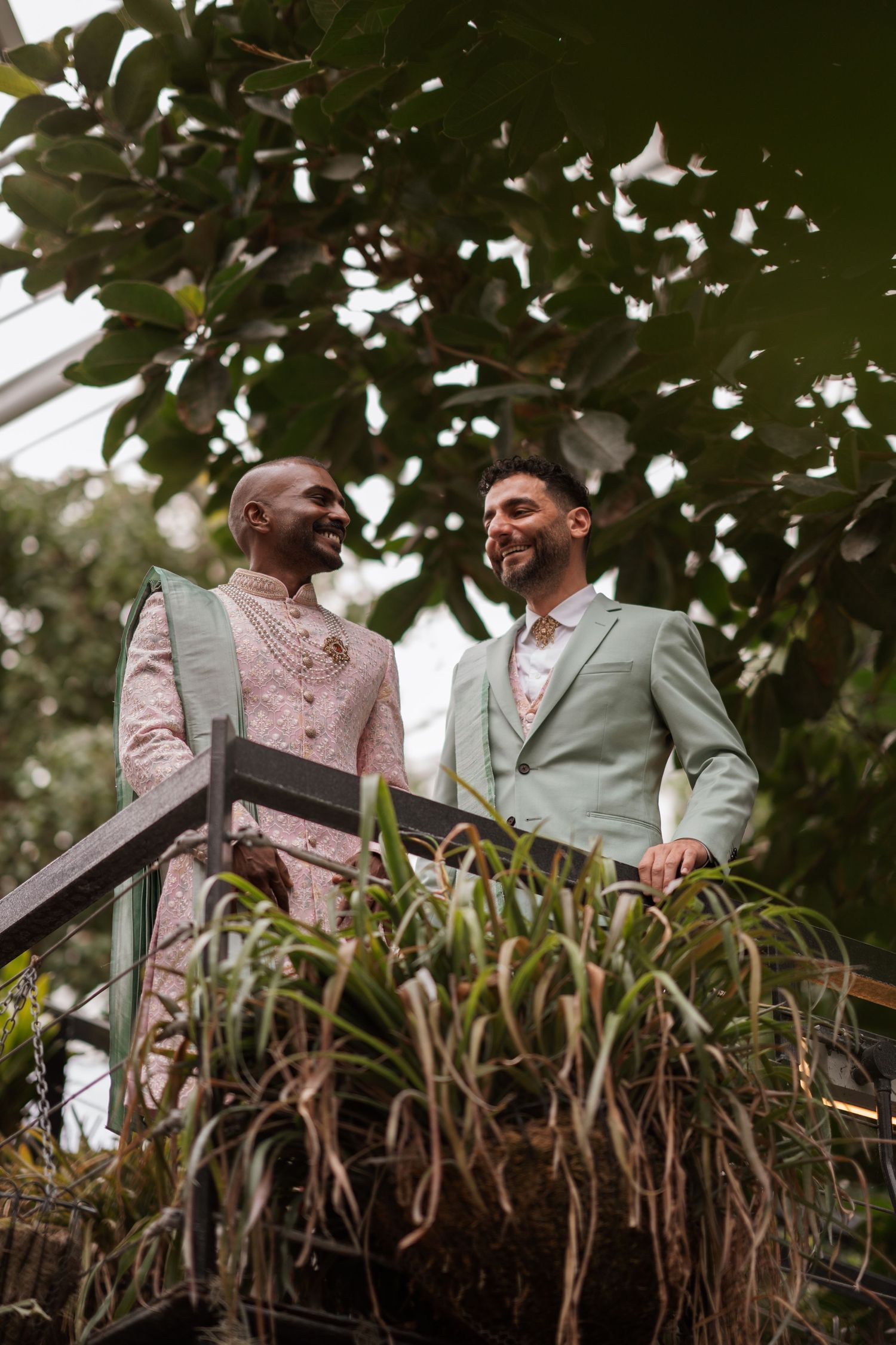 Two people in formal attire standing together in a lush garden setting.