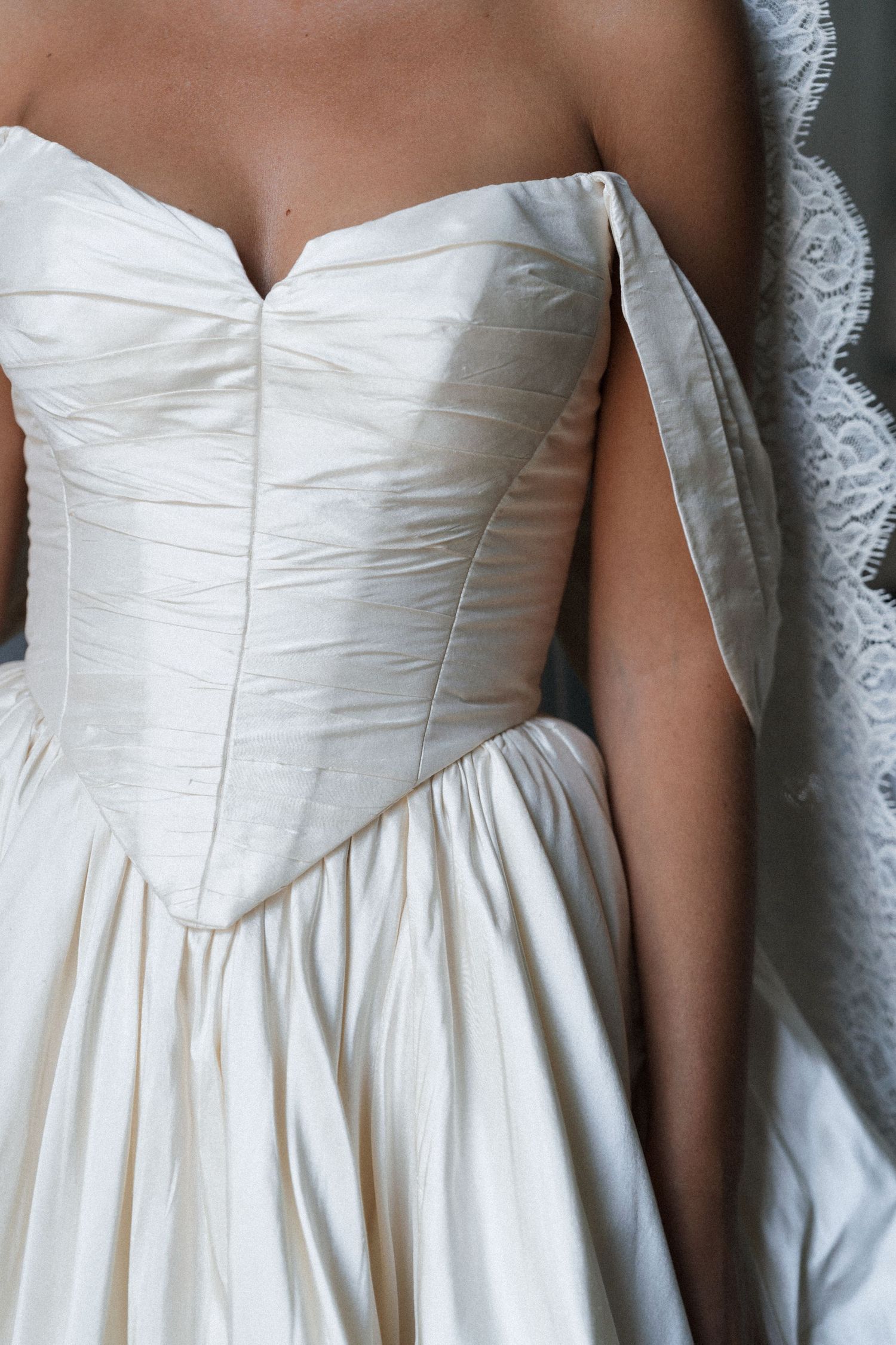 Ivory silk taffeta wedding gown with a strapless sweetheart bodice, draped off-the-shoulder strap, full skirt and delicate lace veil.