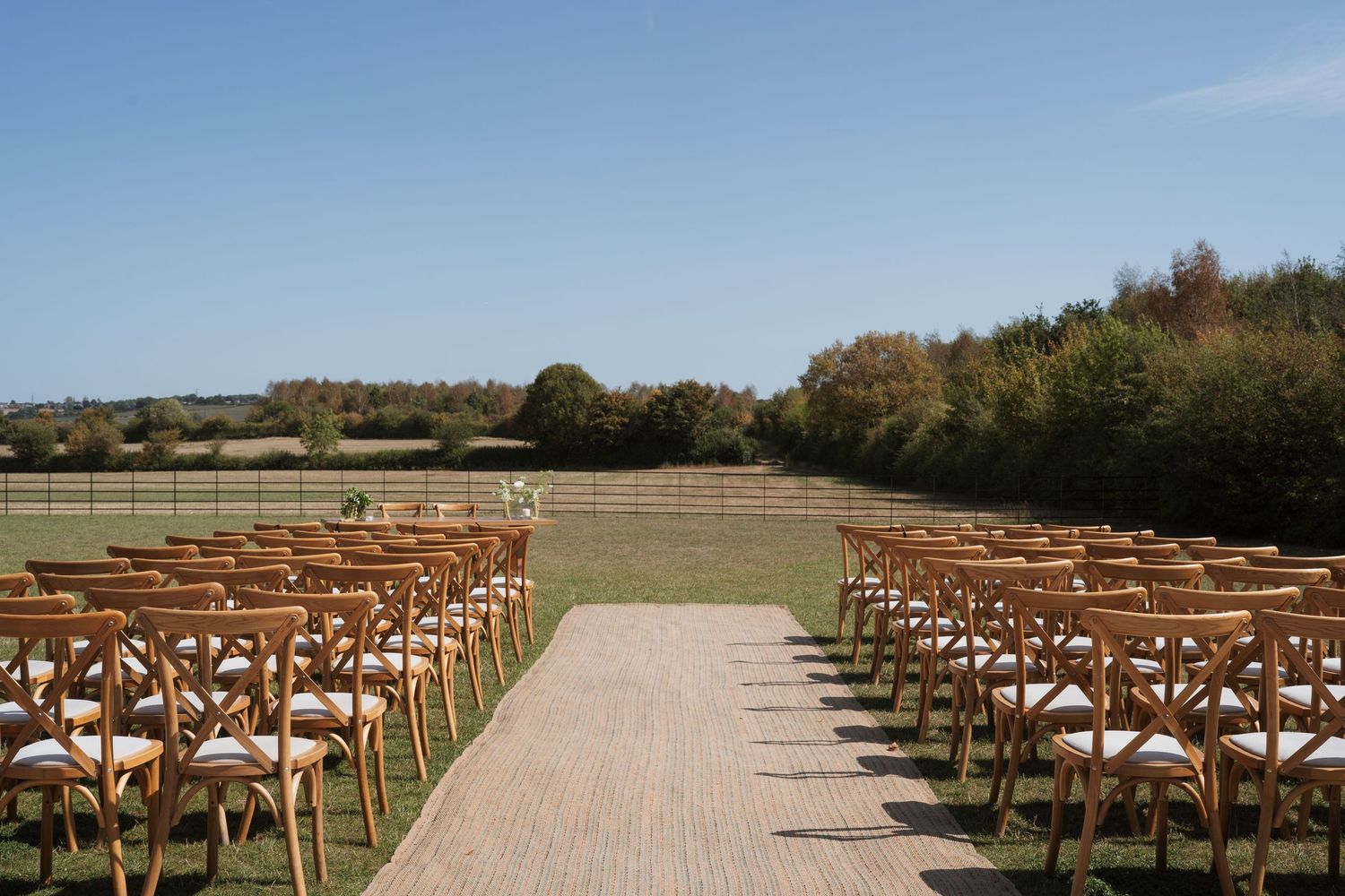 Outdoor wedding ceremony setup with wooden chairs arranged in rows on a natural path.