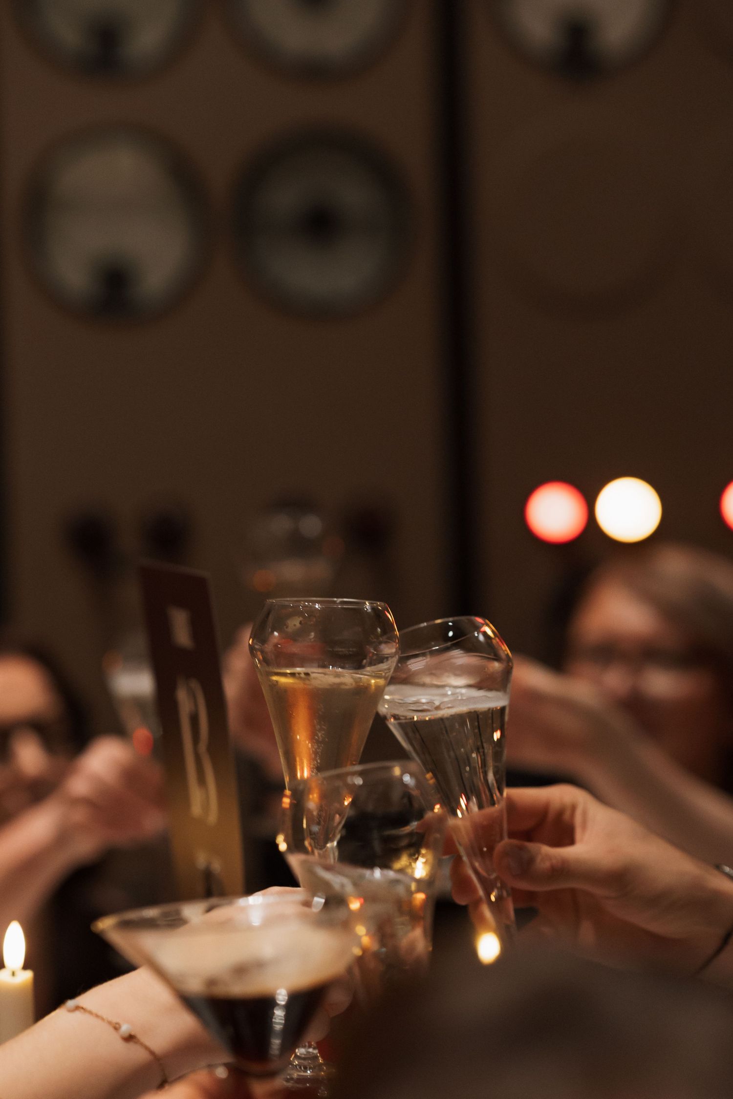 Candlelit glasses clink together in a celebratory toast at an evening reception.