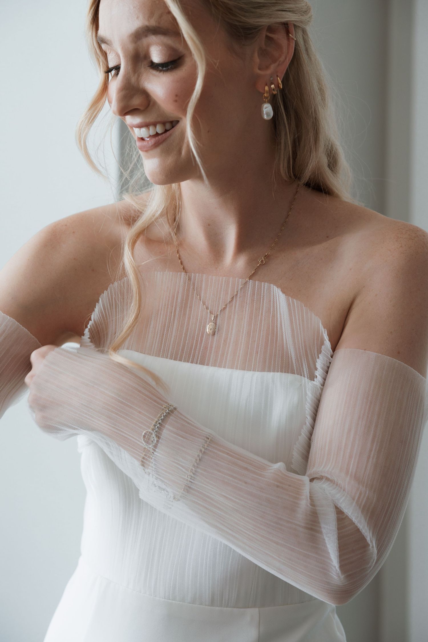 A delicate white tulle dress with off-shoulder details photographed in soft natural light.