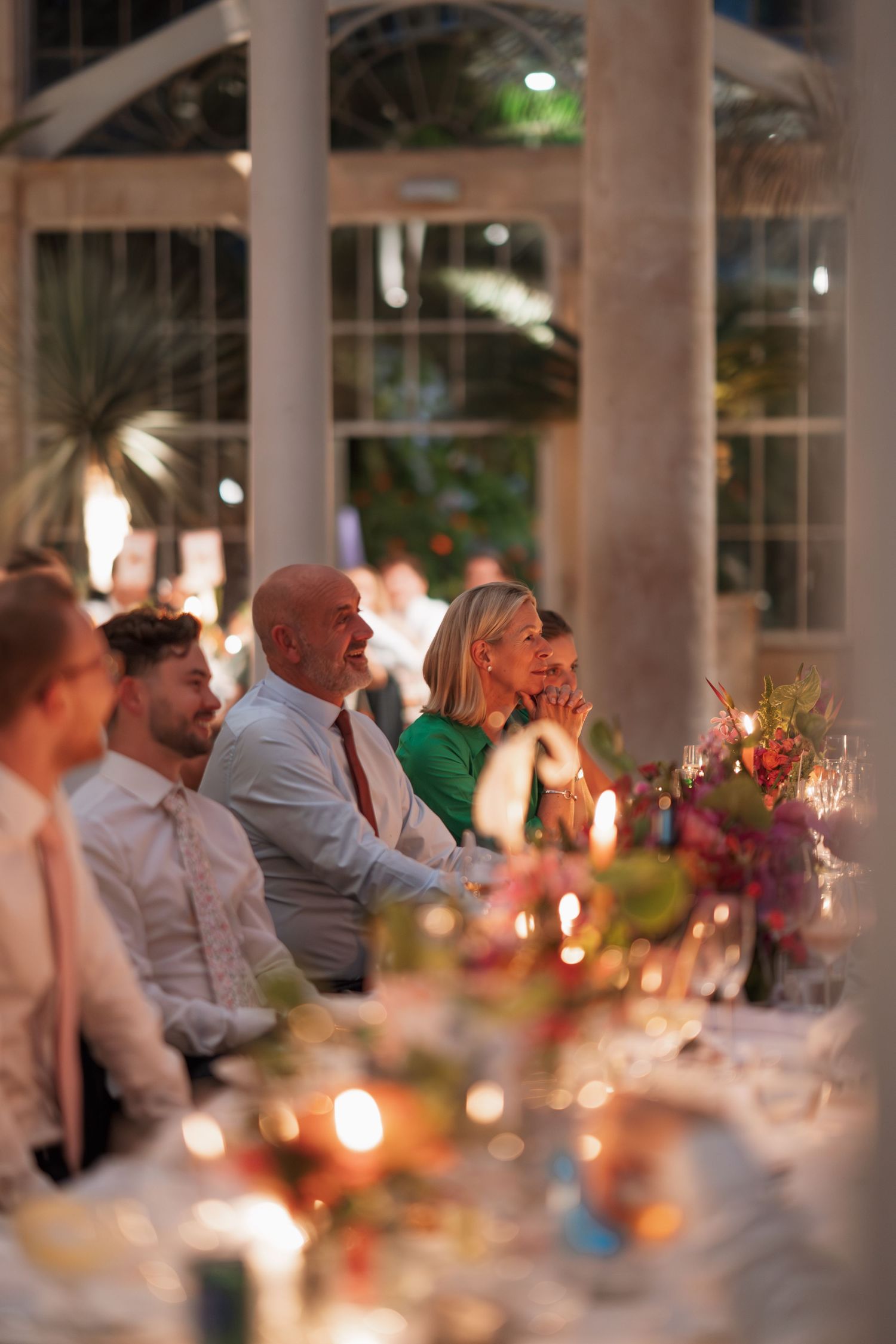 Guests enjoying a festive outdoor dinner party with warm lighting and table decorations.