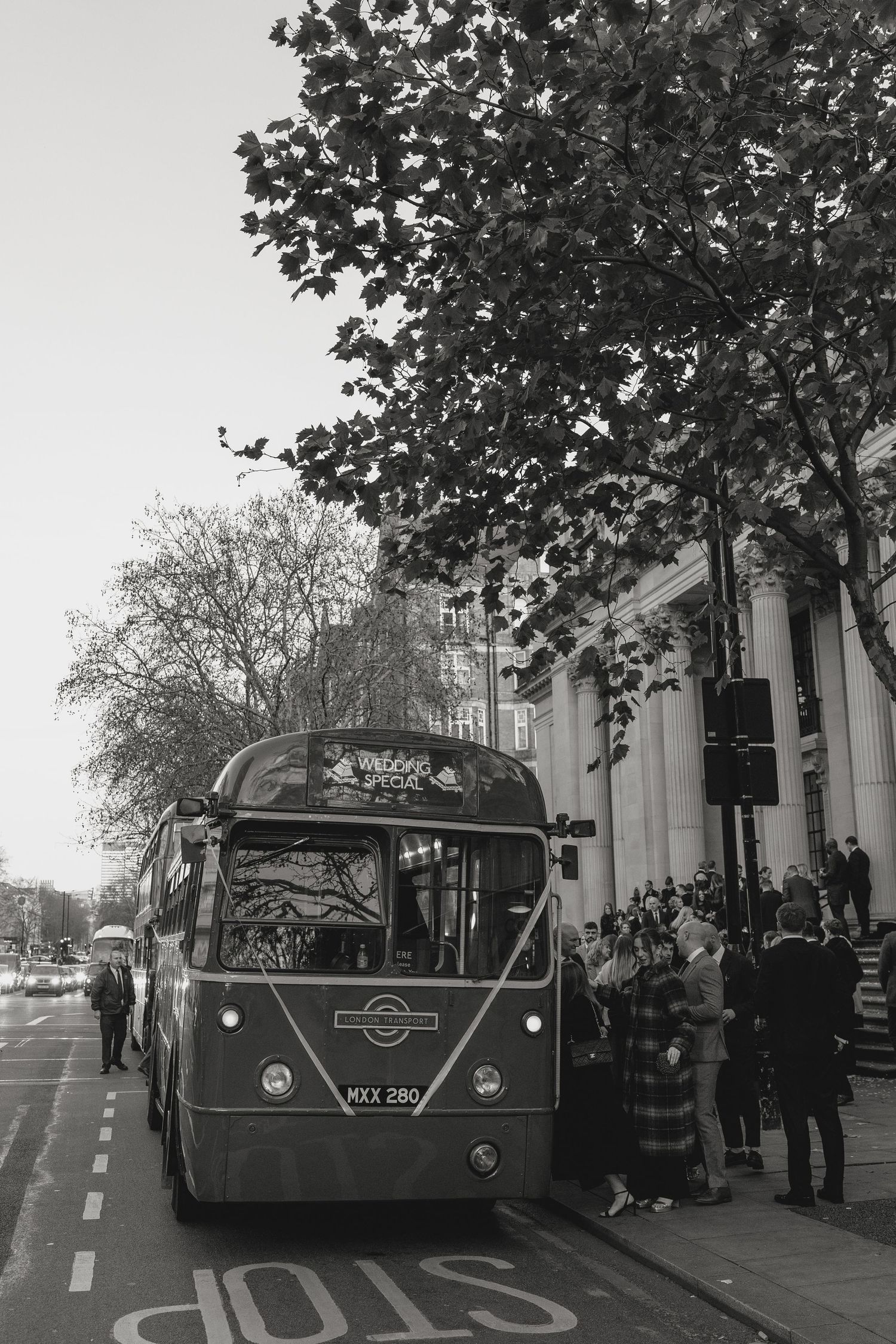 Vintage-style bus parked outside a classical building during an event.