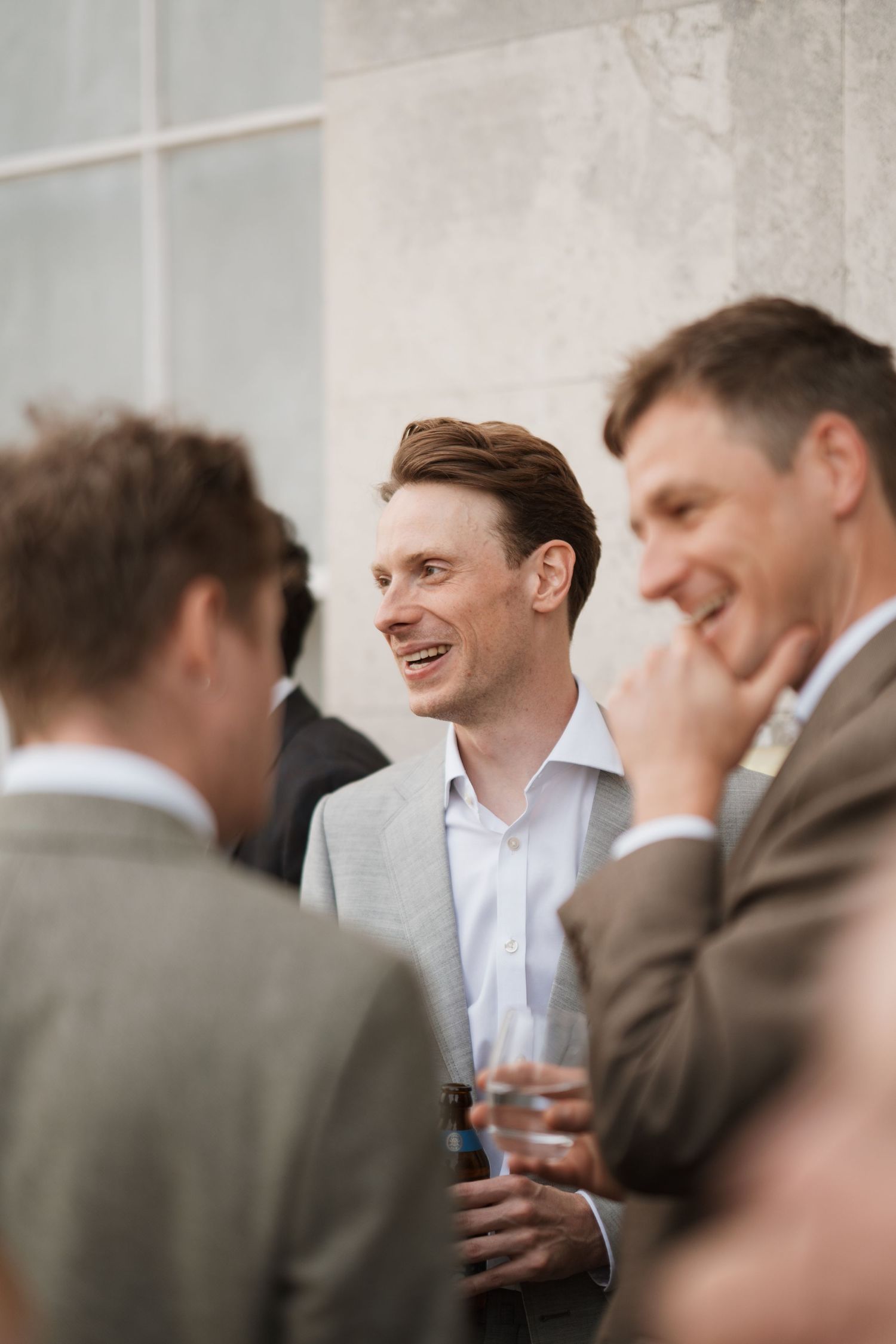 A group of men in formal attire socializing at an indoor event.