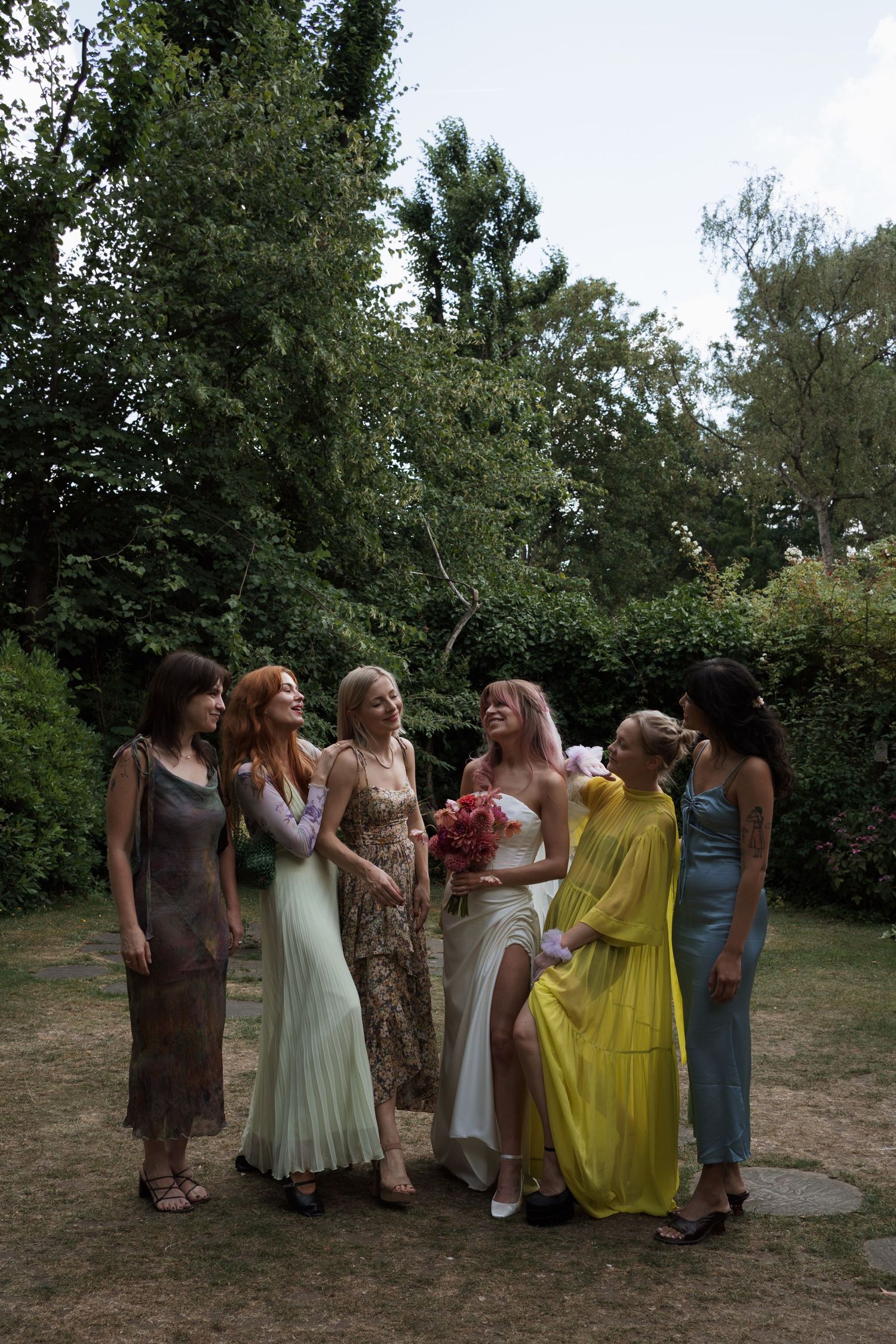 Group of people in colorful dresses posing together outdoors in summer.