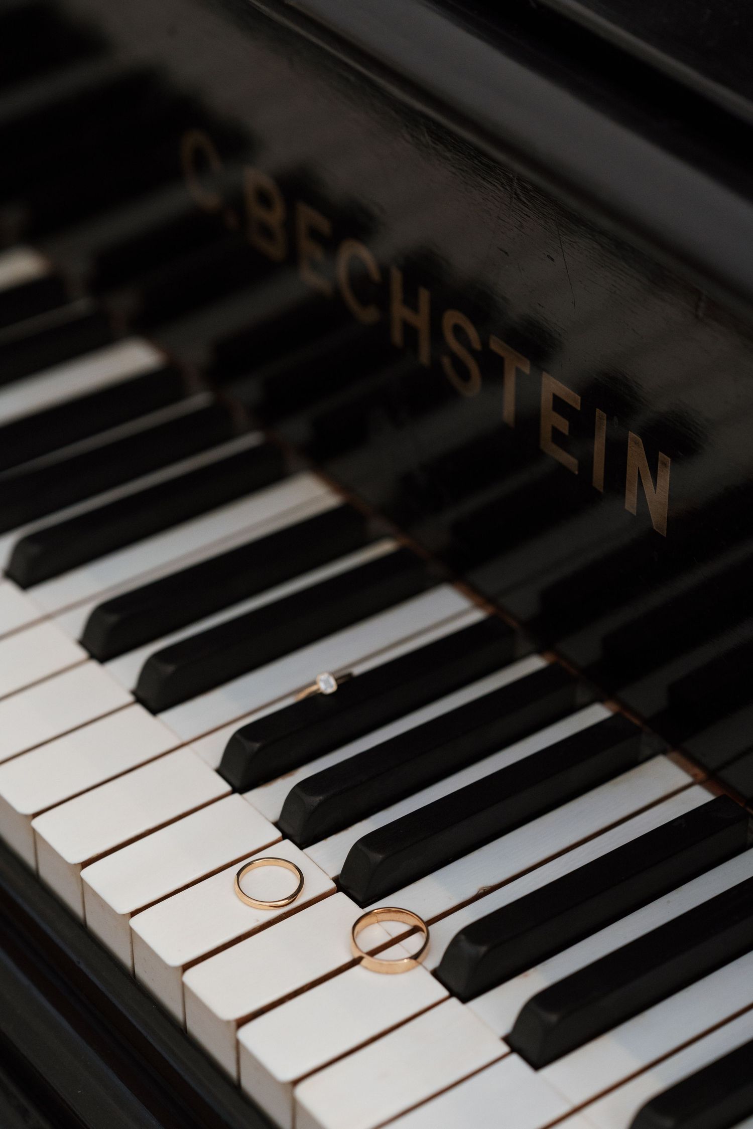Two gold wedding rings placed on black and white piano keys.