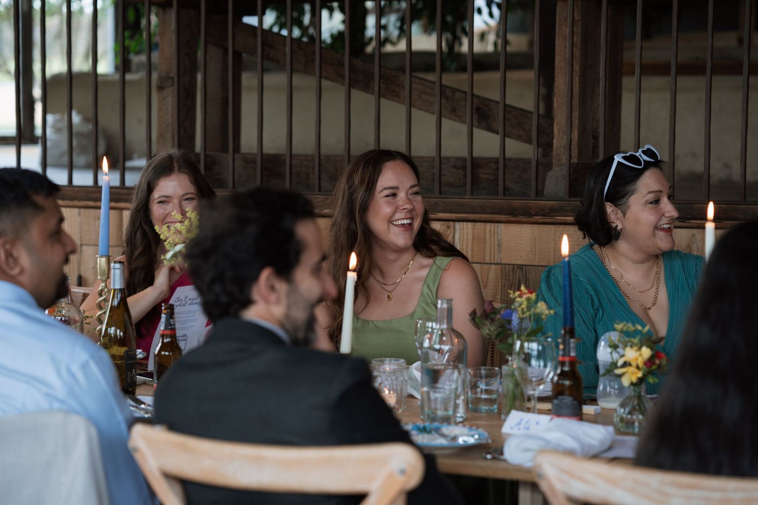 Reception guests seated at long tables decorated with floral centerpieces.