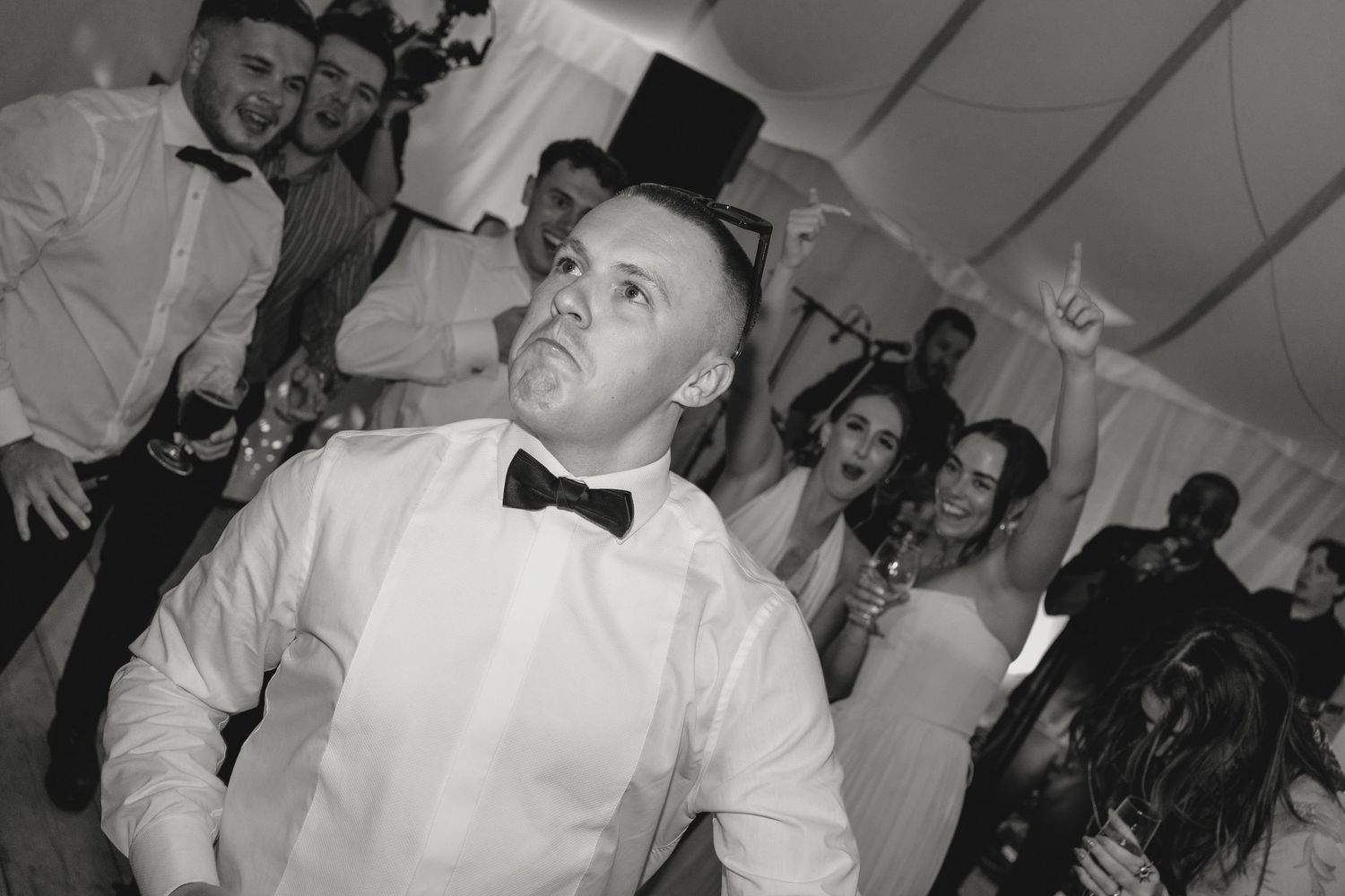 Wedding guests dancing and celebrating on a crowded dance floor.