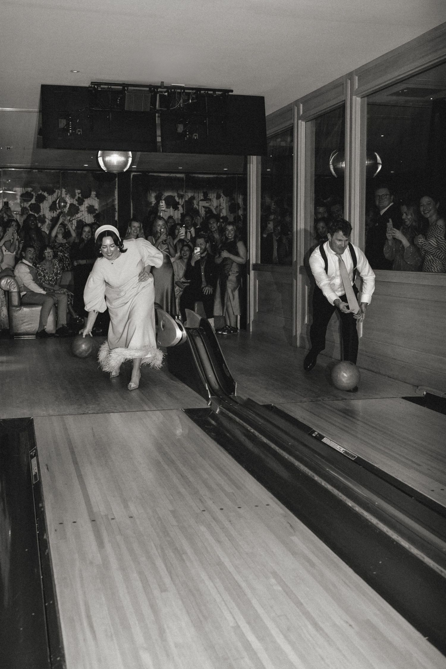 Vintage black and white photo of people bowling in a retro bowling alley.