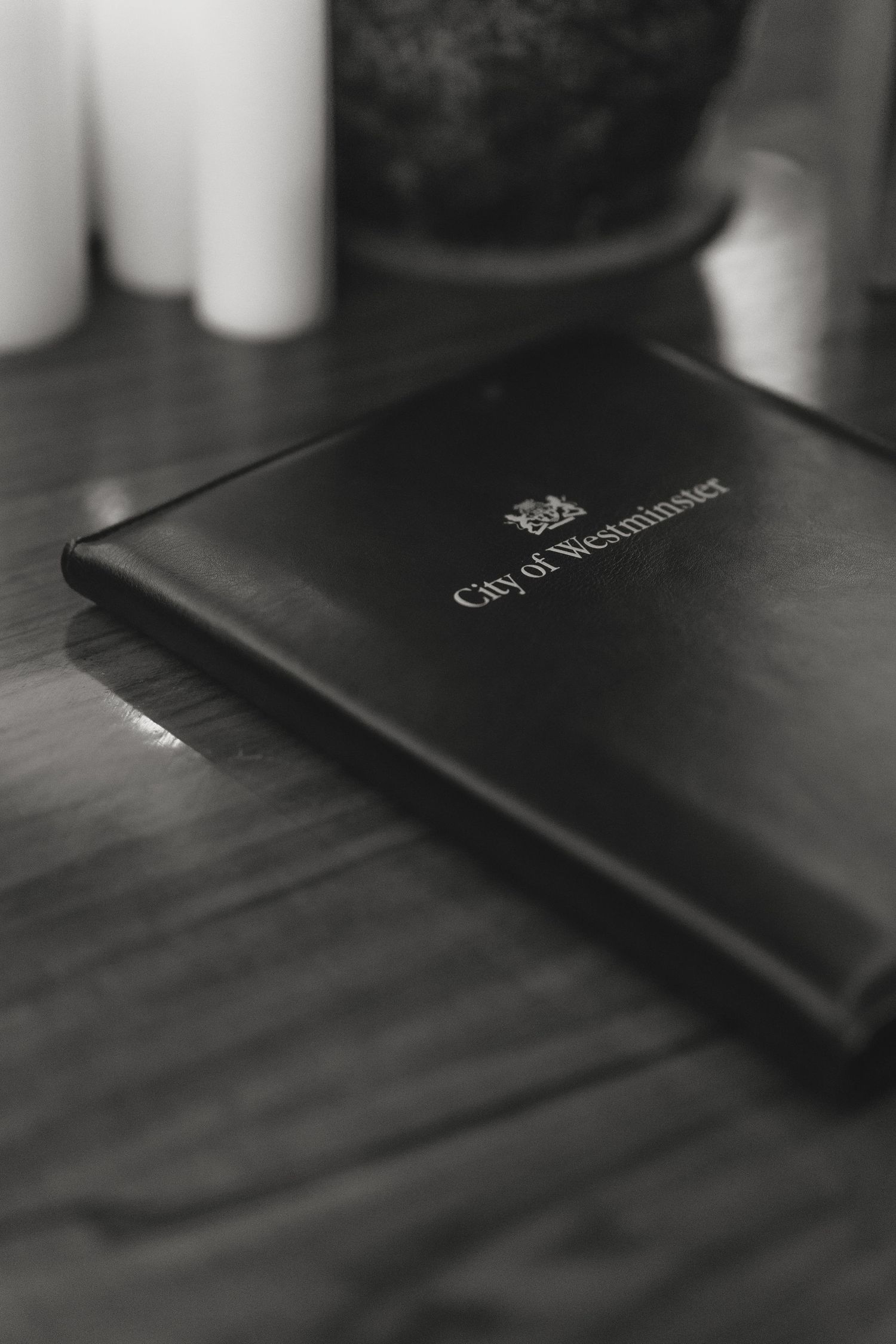 Black leather-bound city documents book on wooden surface.