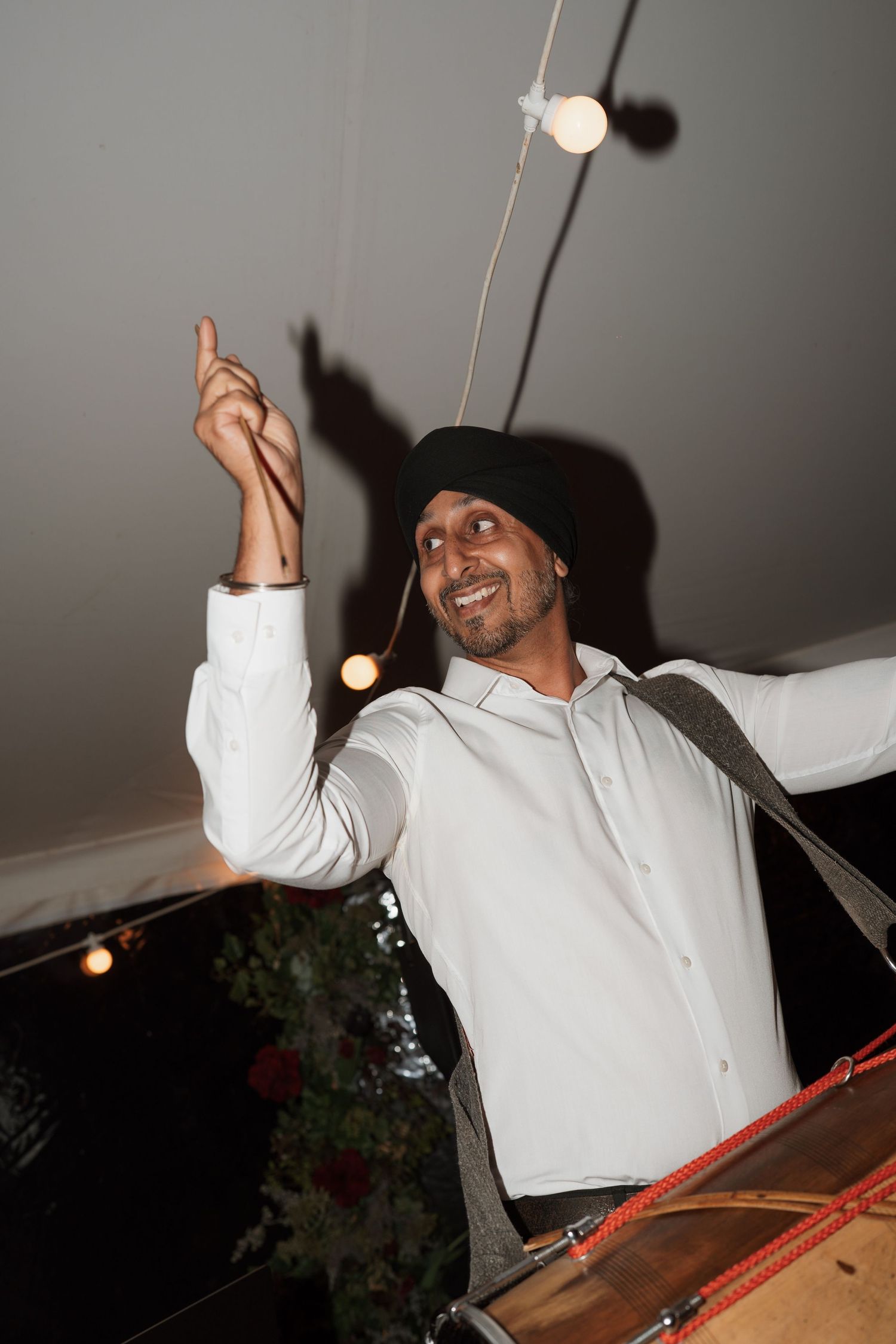 Wedding guest in white shirt dances energetically under ambient lighting.
