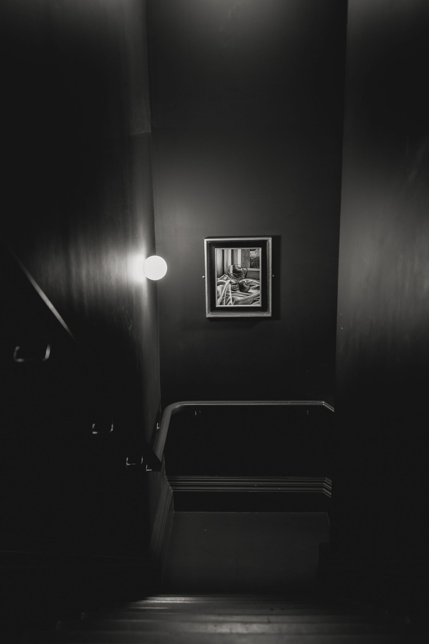 Dark moody interior with single light fixture and framed artwork.