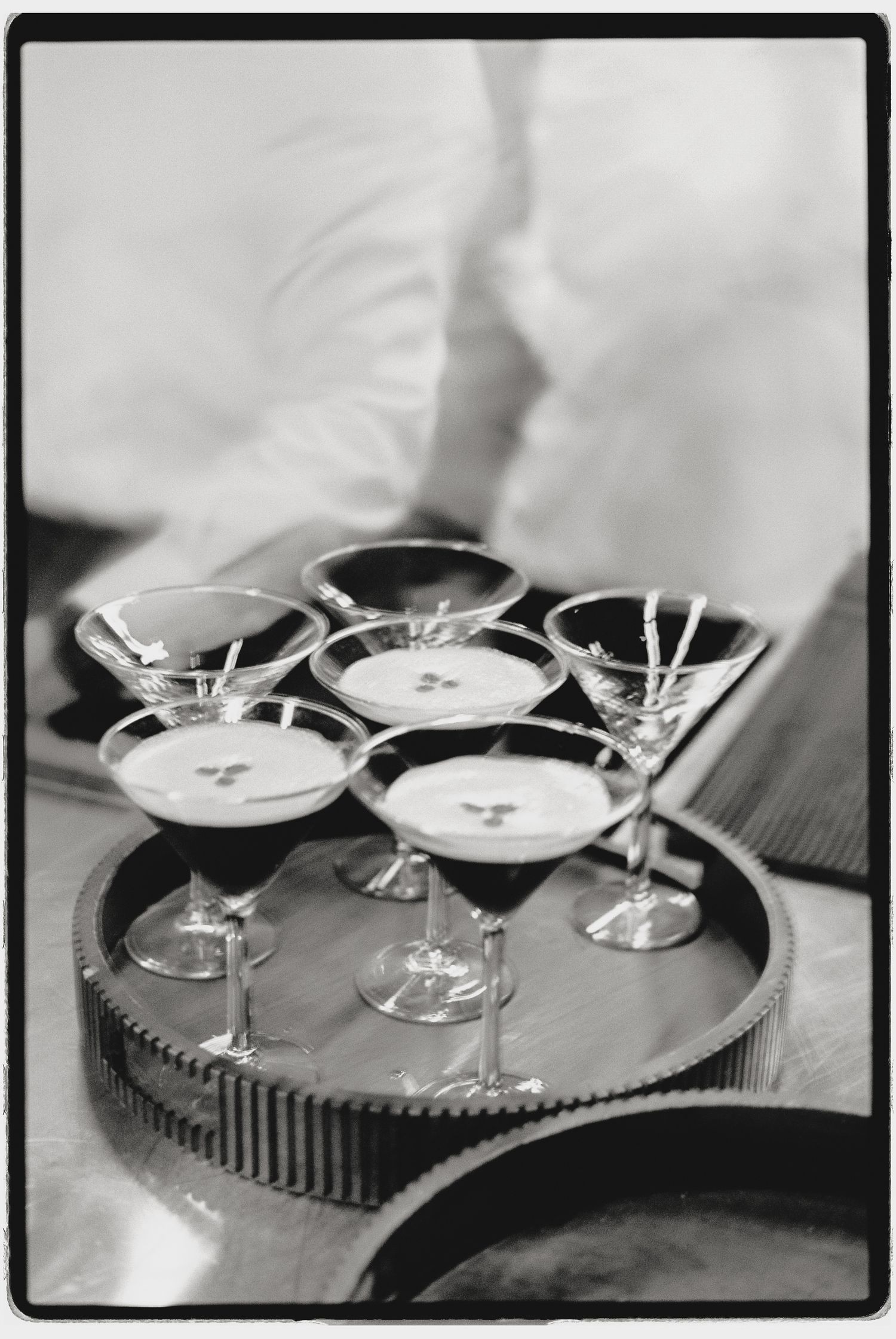 Black and white photo of martini glasses arranged on a circular serving tray.