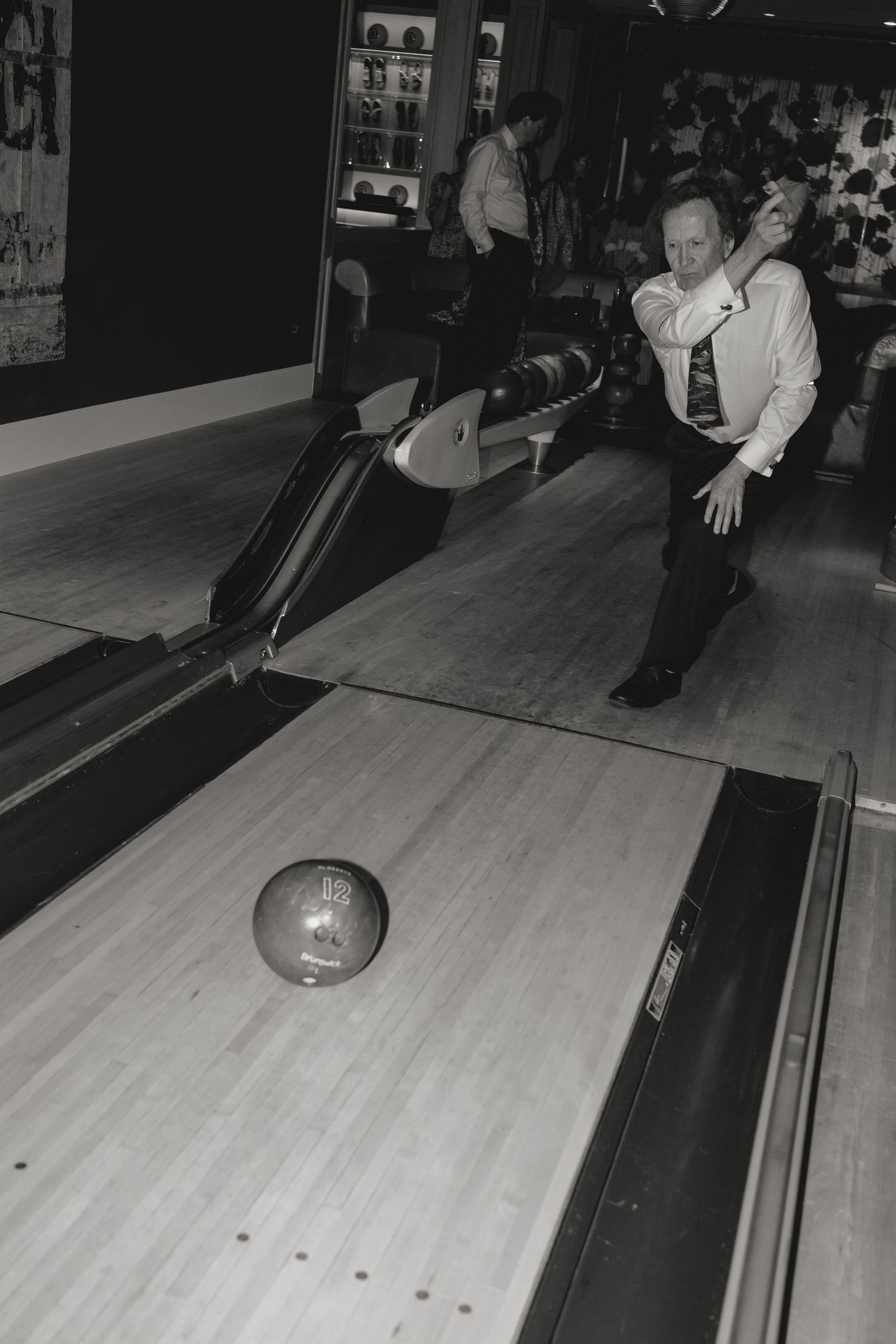 A bowling ball rolls down a wooden lane towards pins in a bowling alley.