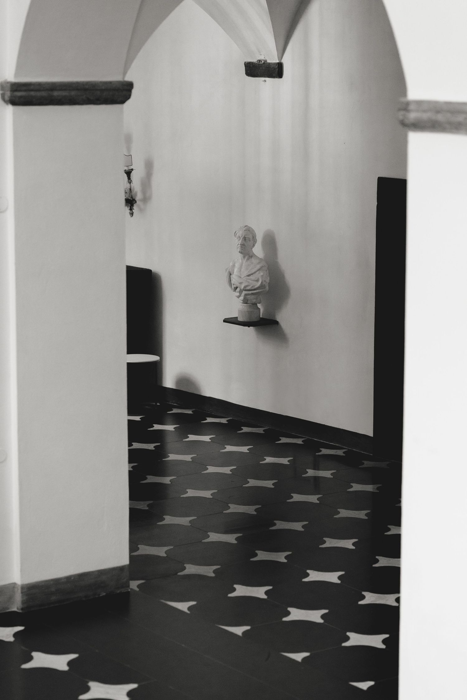 White room interior with black star patterns on the floor and arched doorways.