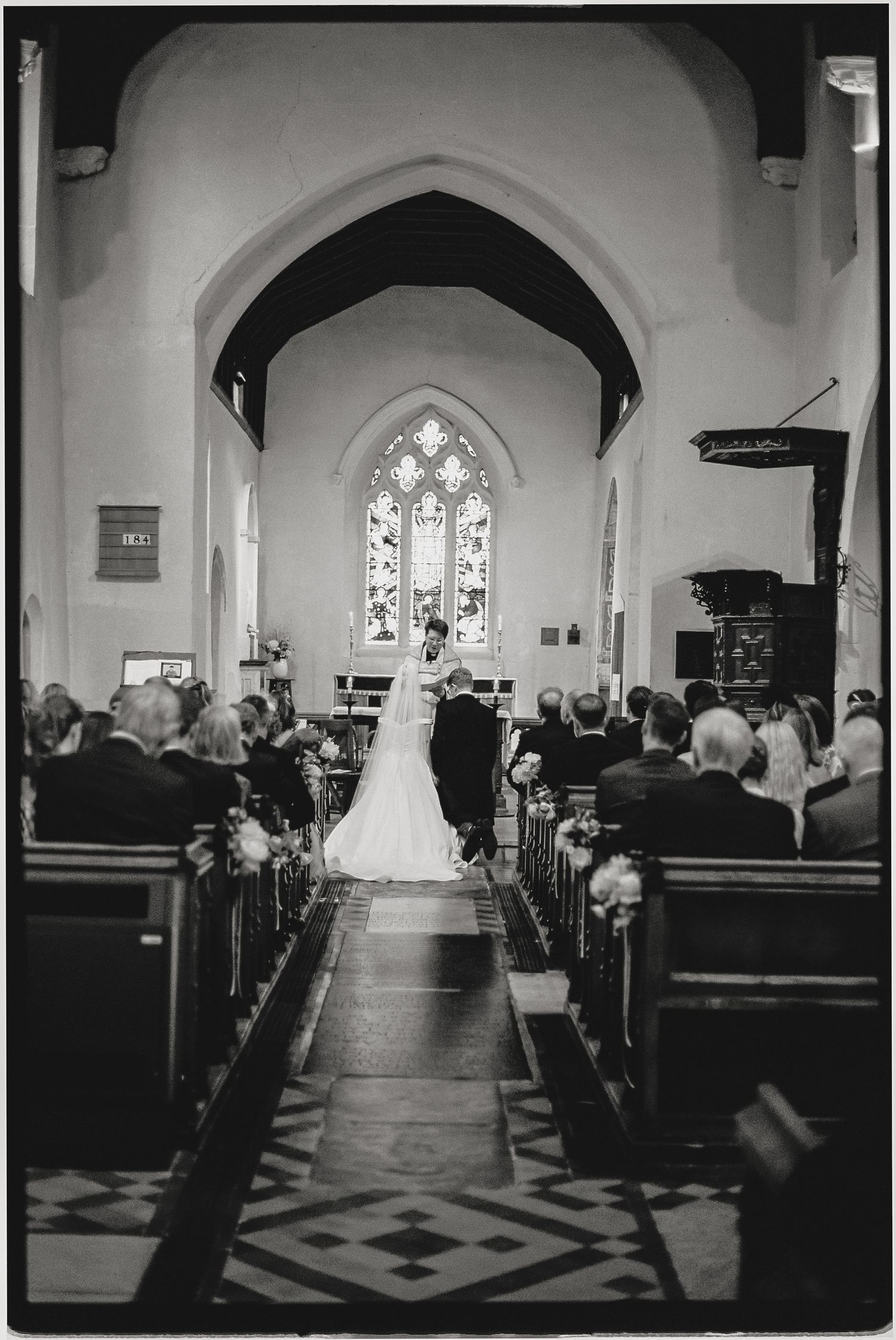 Black and white photo of a bride and groom at the altar of a traditional church during their wedding ceremony.