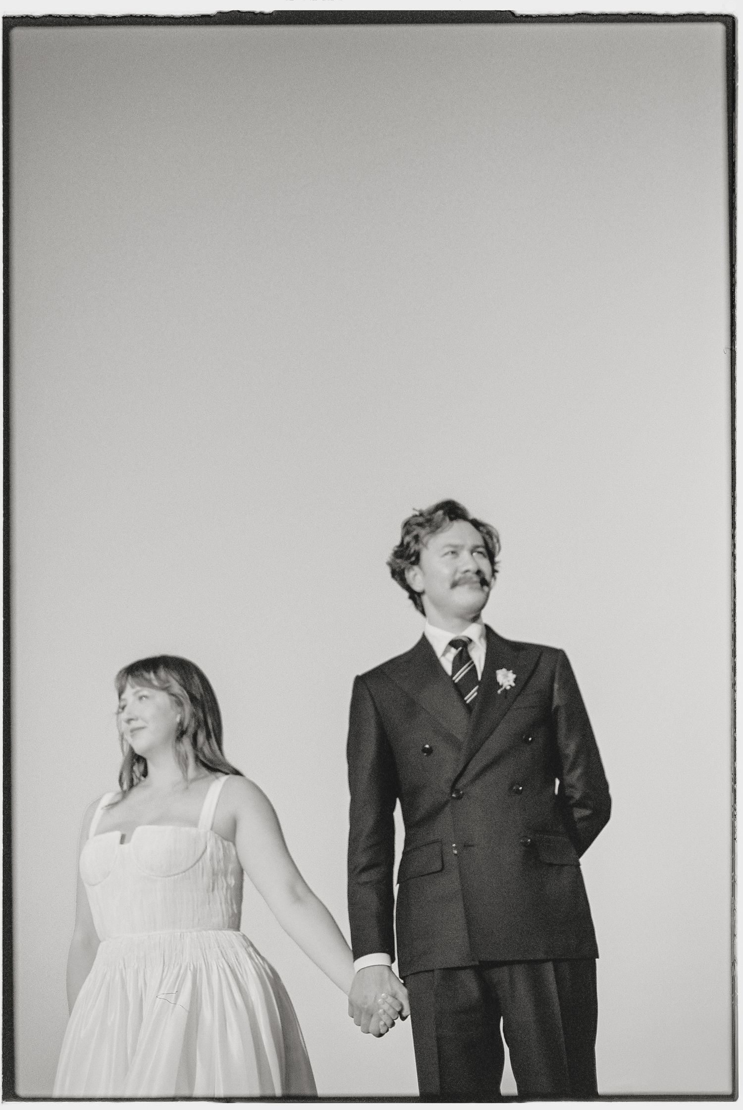 Minimalist black and white portrait against white background showing formal attire.