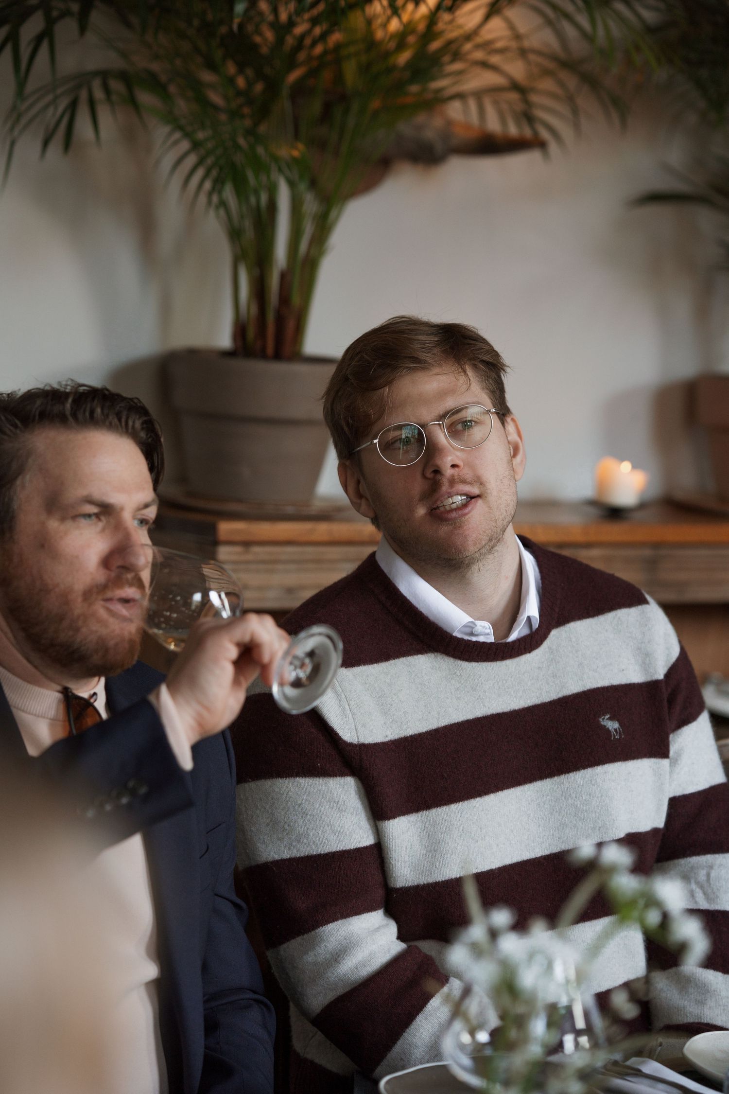 Group enjoying drinks and conversation at a casual gathering in warm lighting.