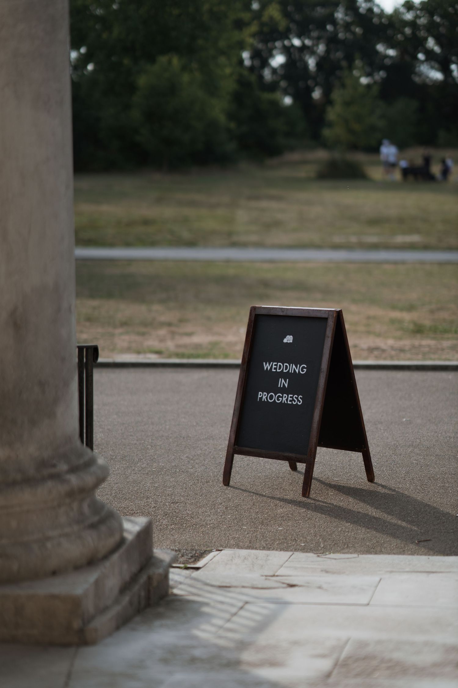 A black chalkboard sign with the word 'WEDDING' displayed at an outdoor venue.