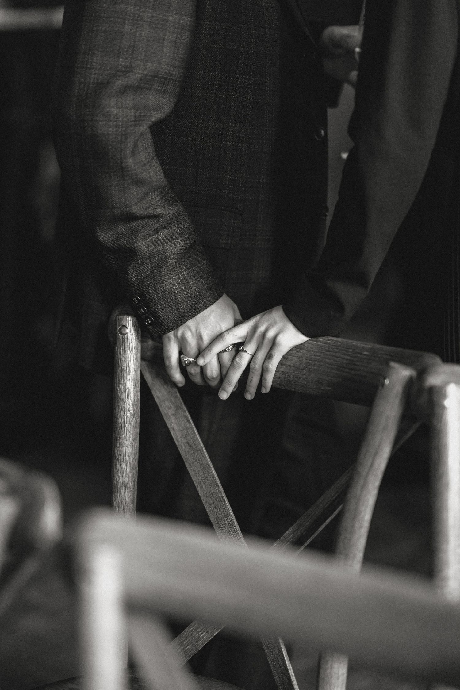 Close-up black and white detail of hands on wooden furniture.