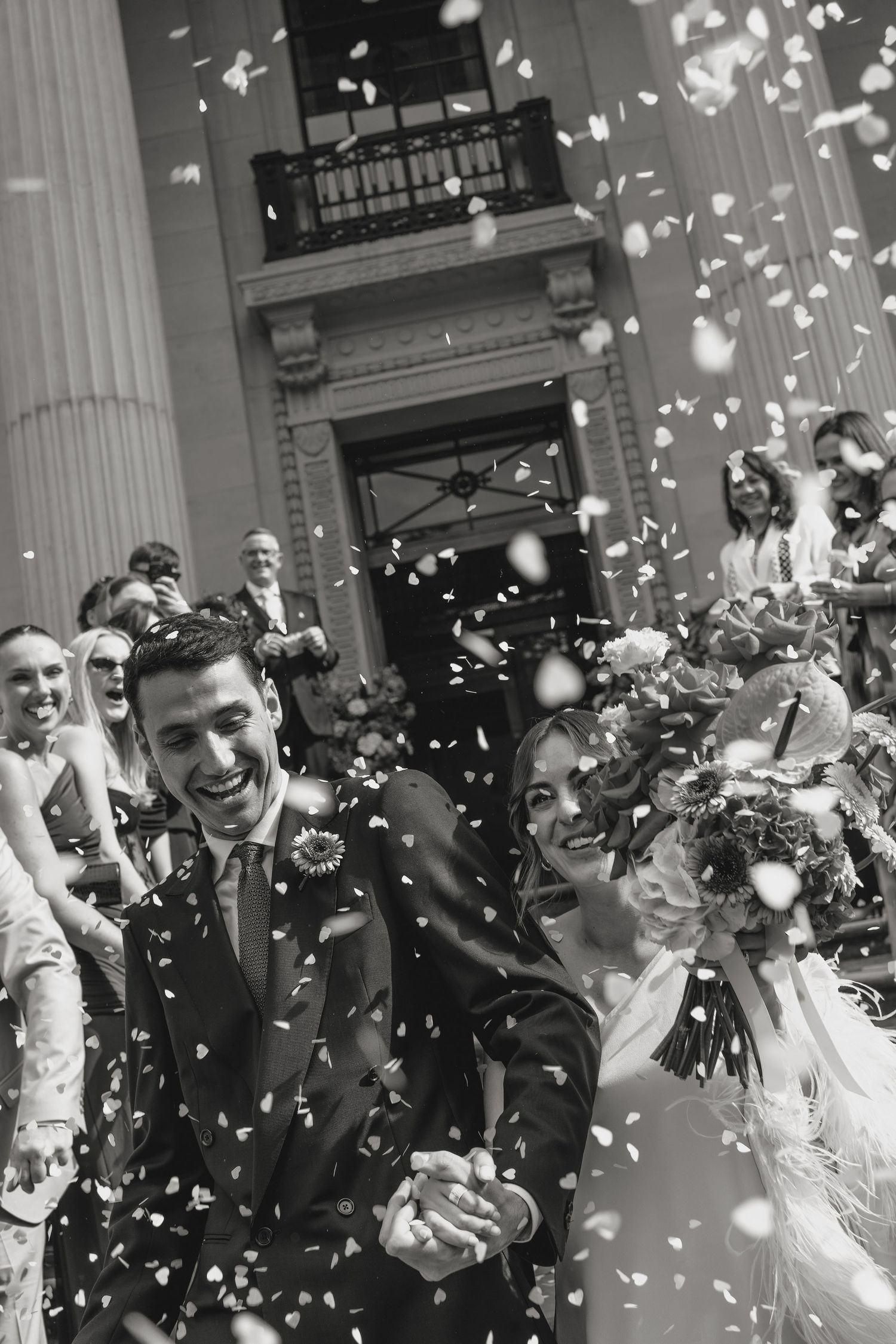 Joyful celebration with confetti shower outside classical building.