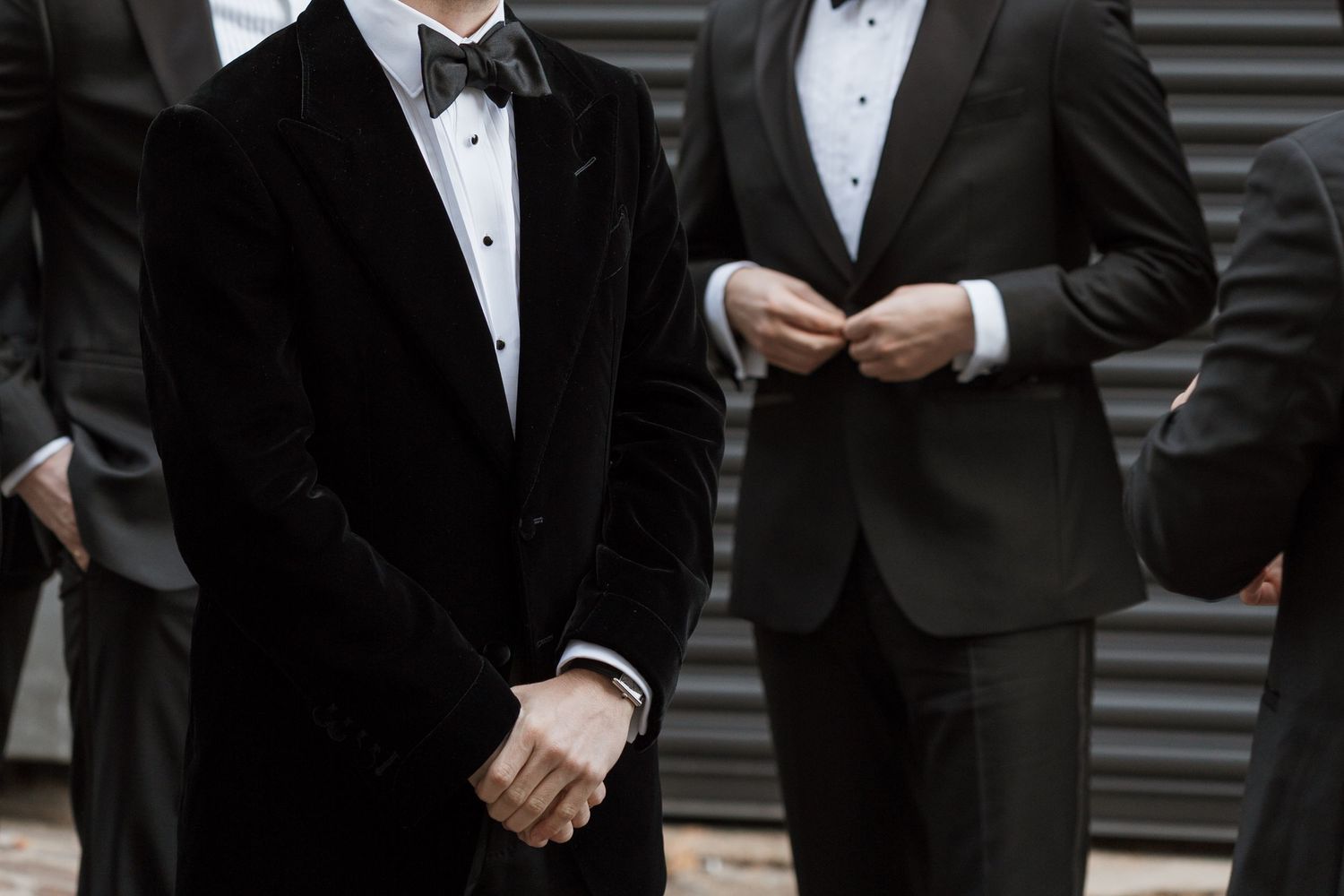 Men in black tuxedos and bow ties standing in conversation at a formal event.
