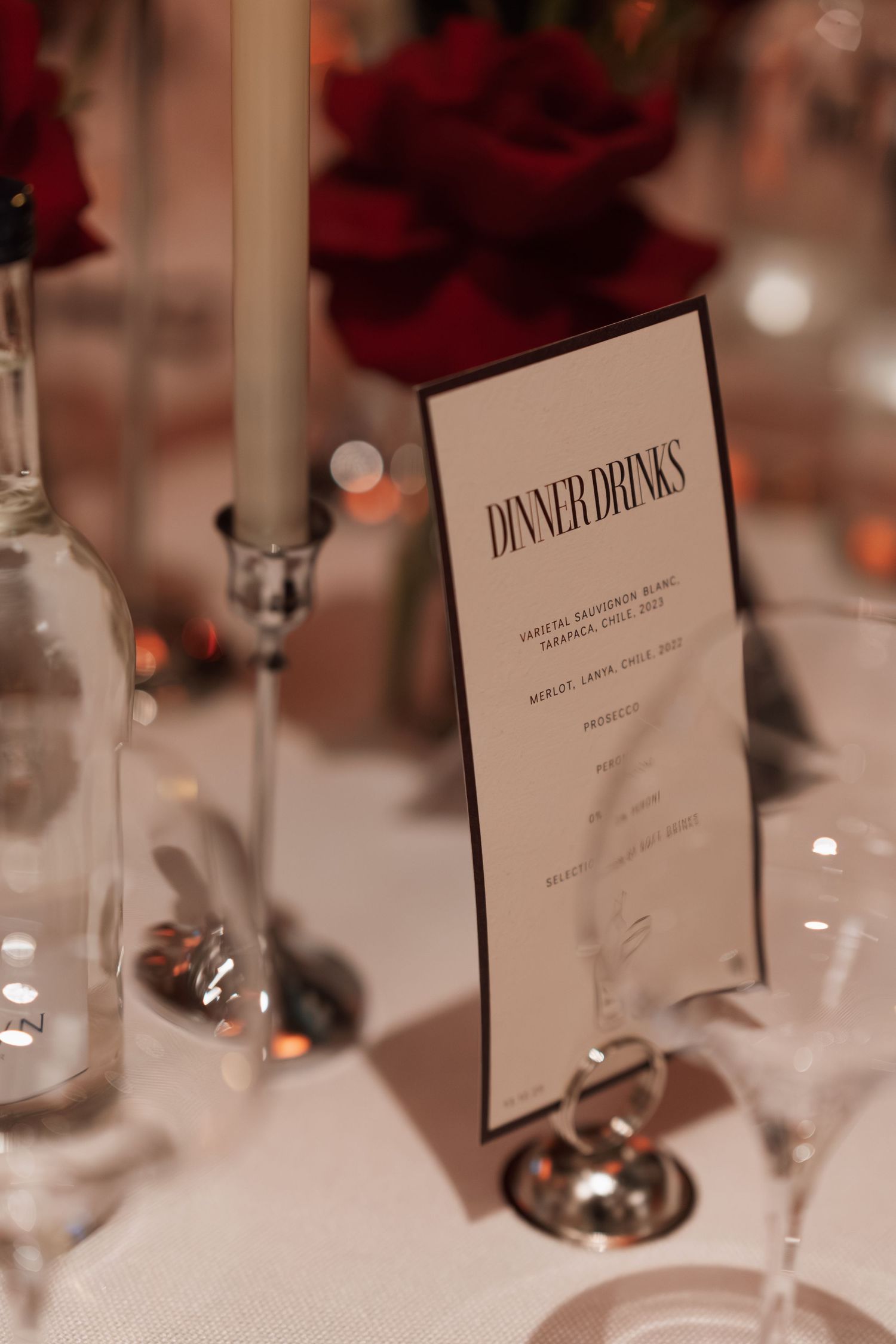 Close-up of formal dinner menus and place settings with red floral accents.