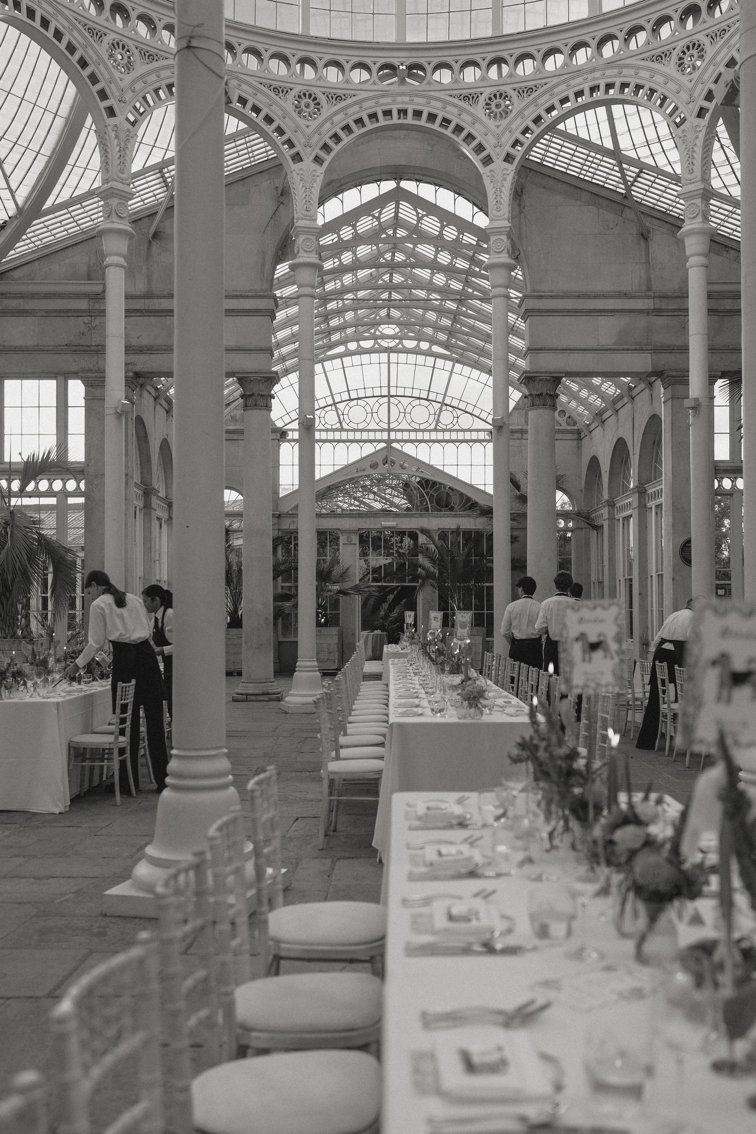 Elegant white conservatory interior set up for wedding reception with tables and chairs.