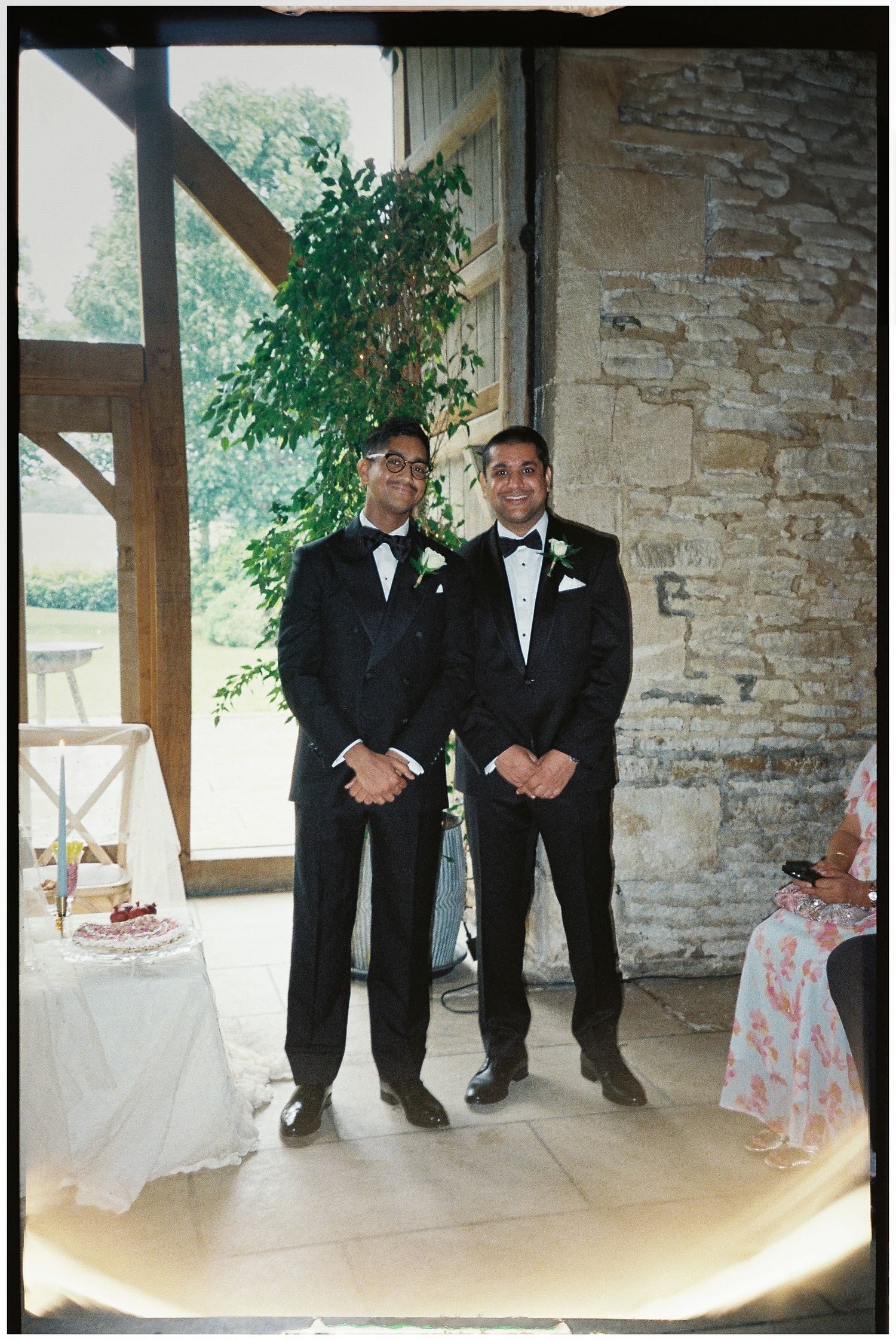 Groomsmen in tuxedos standing in a rustic stone building.