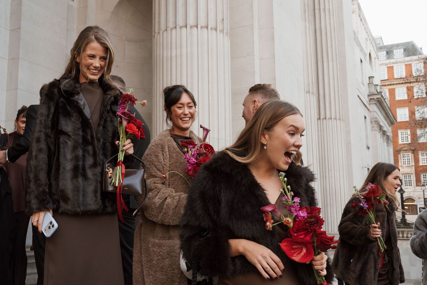 People gathering between classical columns at a formal event.