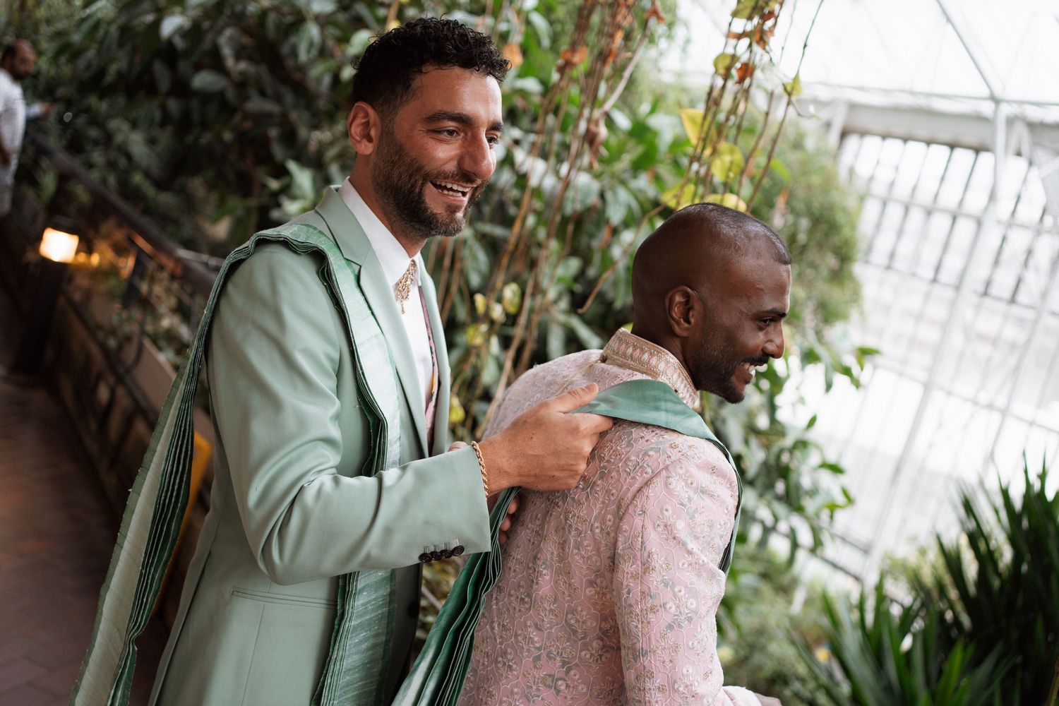 Candid moment captured in greenhouse setting with natural light filtering through foliage.