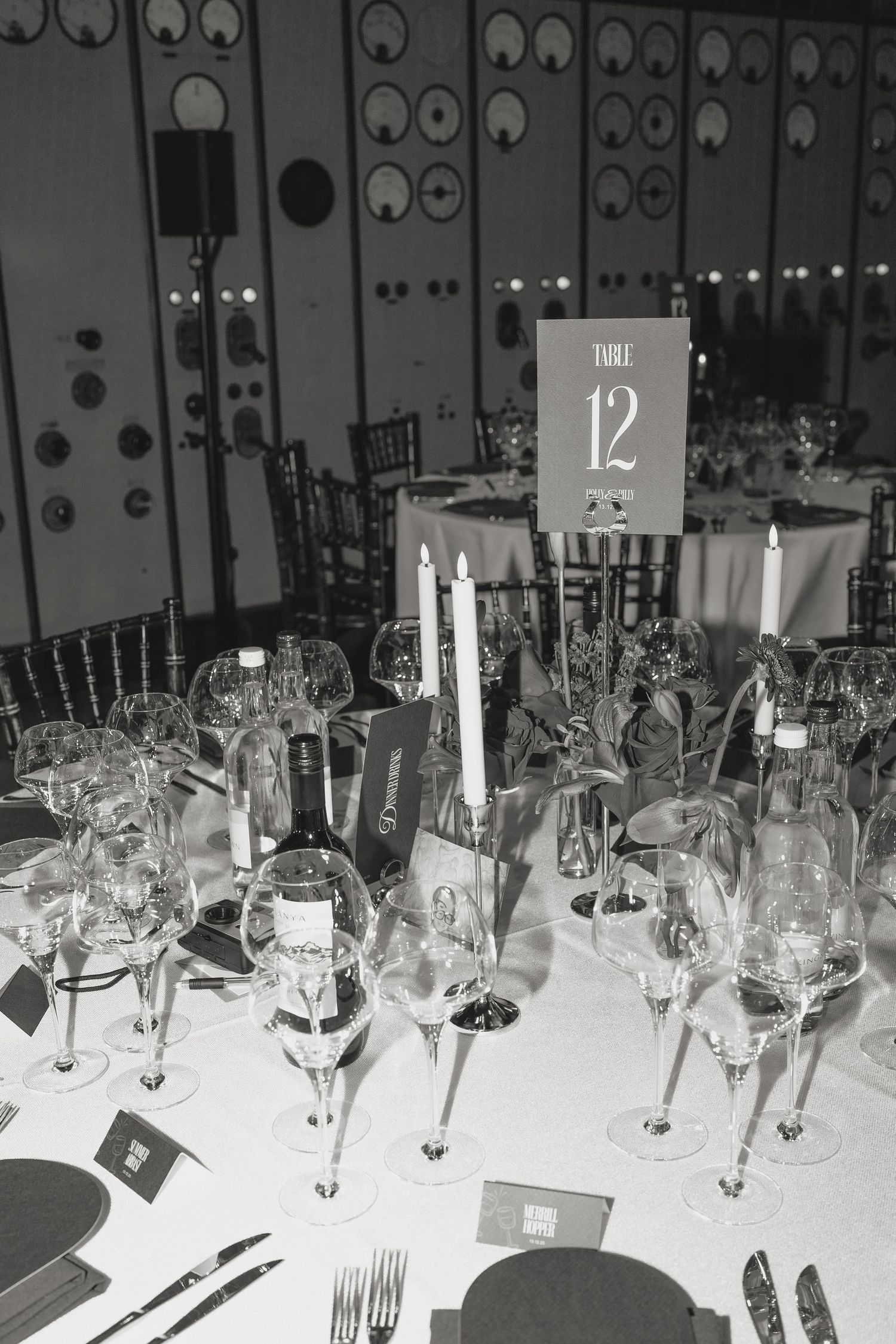 Black and white photo of formal table settings with wine glasses and place cards.