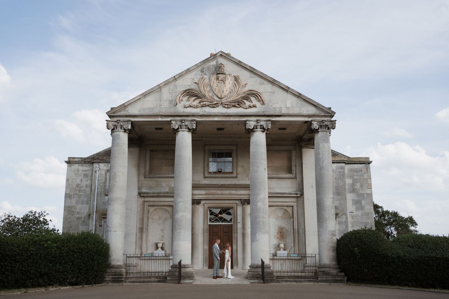 Classical white stone building with columns and pediment against blue sky.