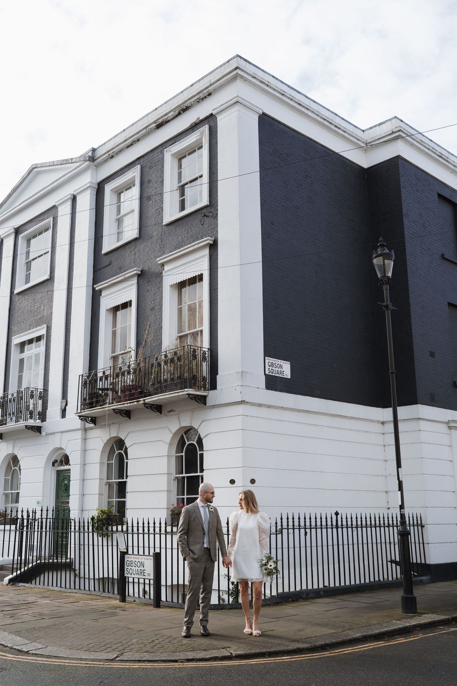 A couple standing in front of a black and white Georgian building with iron railings.