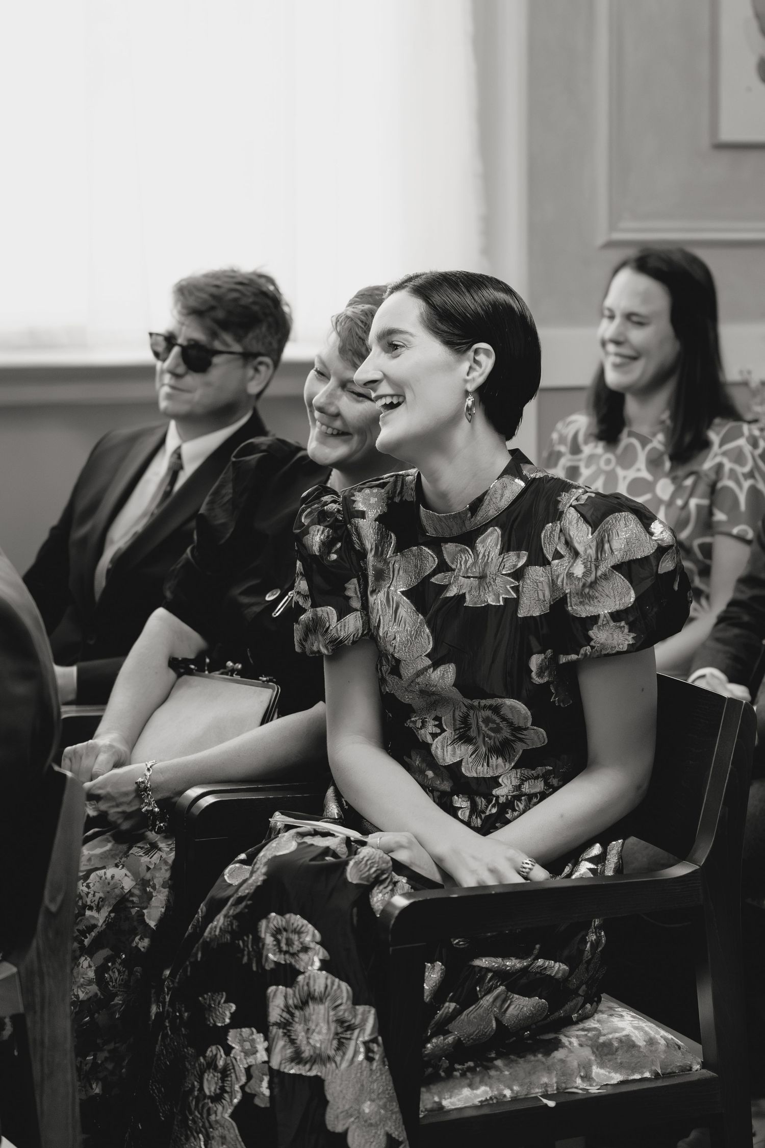 Wedding guests in formal attire seated in rows during a ceremony.