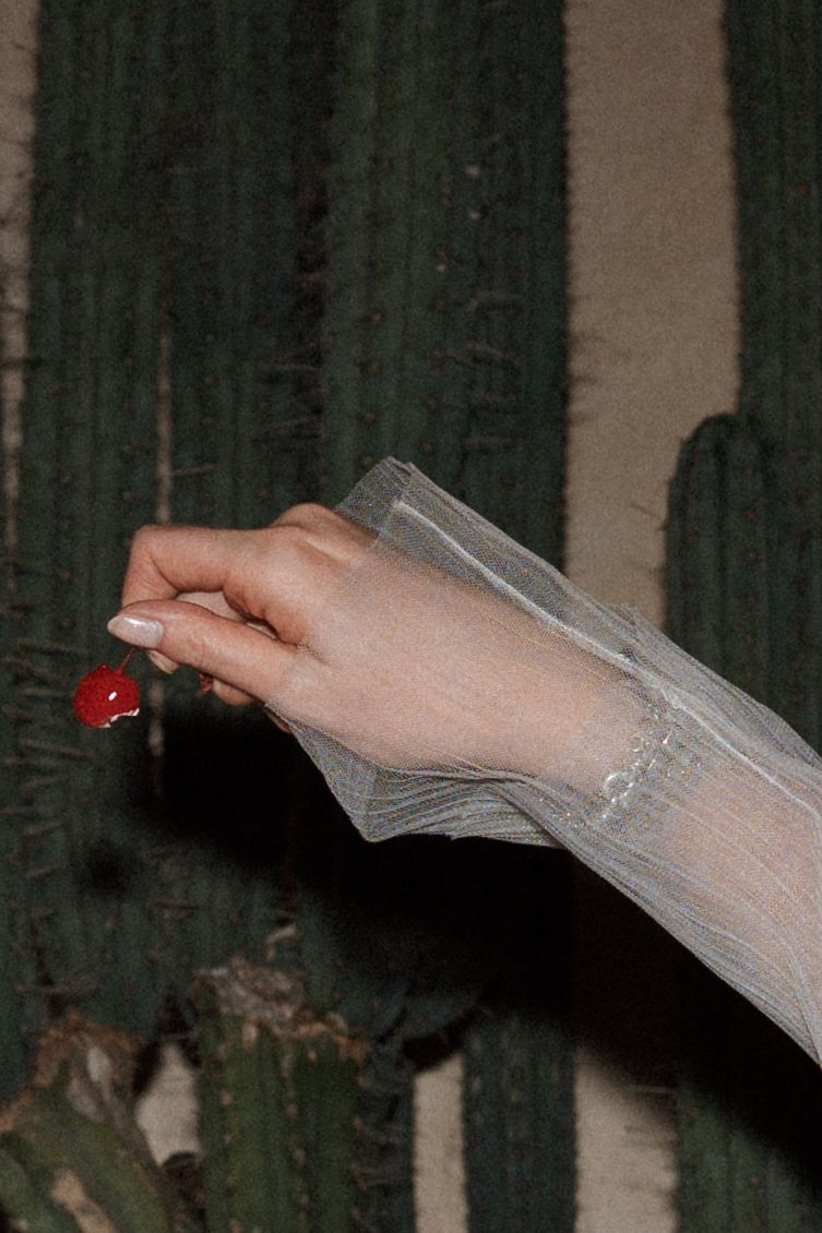 Close-up of hands holding a delicate veil against a dark background.